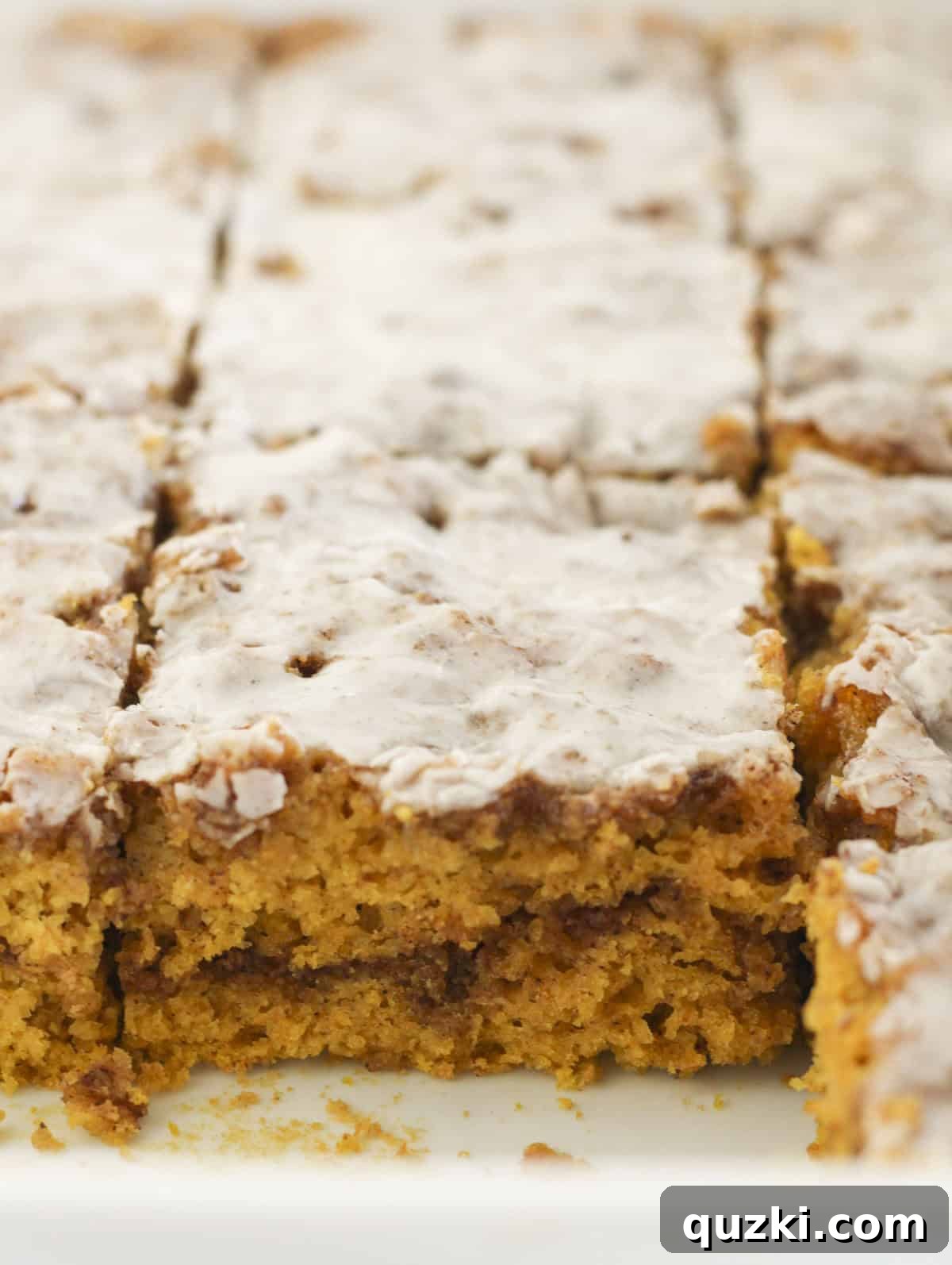 A delicious pumpkin cinnamon roll cake, perfectly cut into squares and ready to serve, showcasing its beautiful layers.