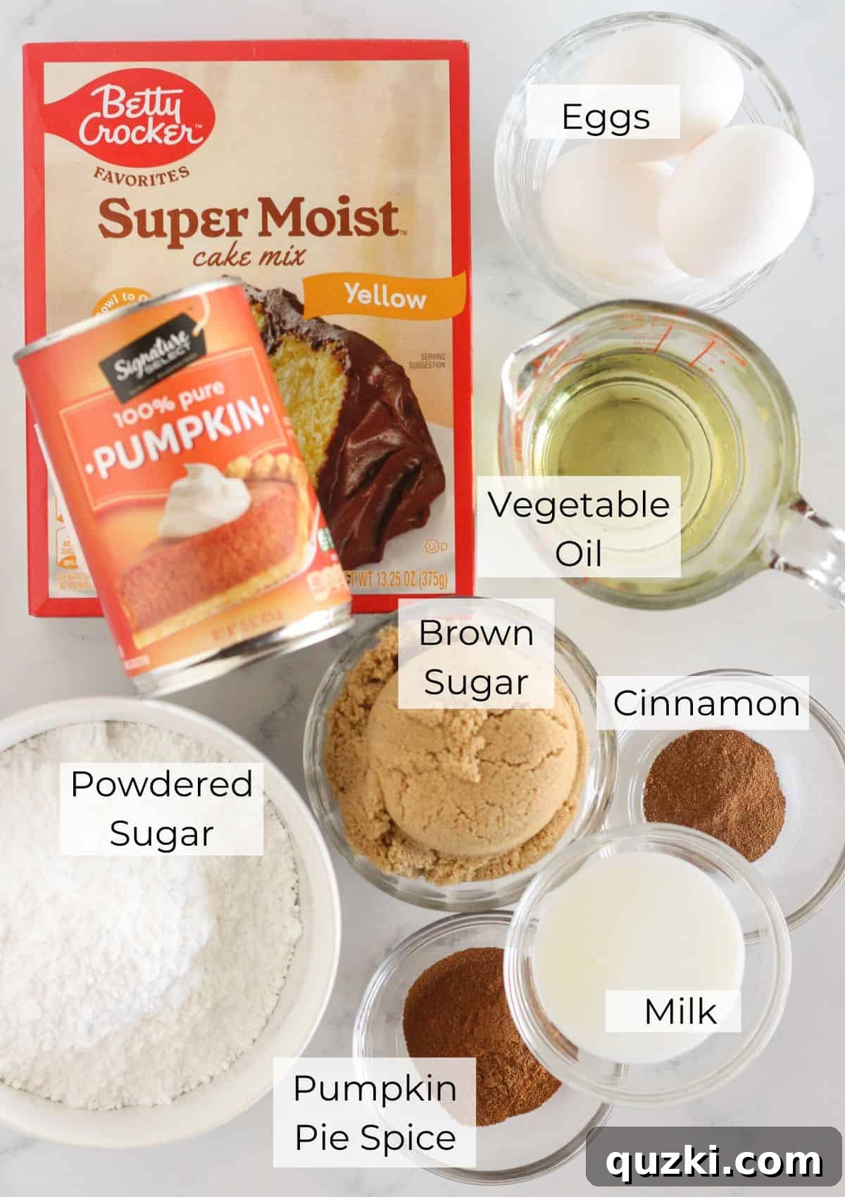 All the necessary ingredients laid out for making the Pumpkin Cinnamon Roll Cake, including a box of yellow cake mix, pumpkin puree, eggs, oil, brown sugar, and spices.