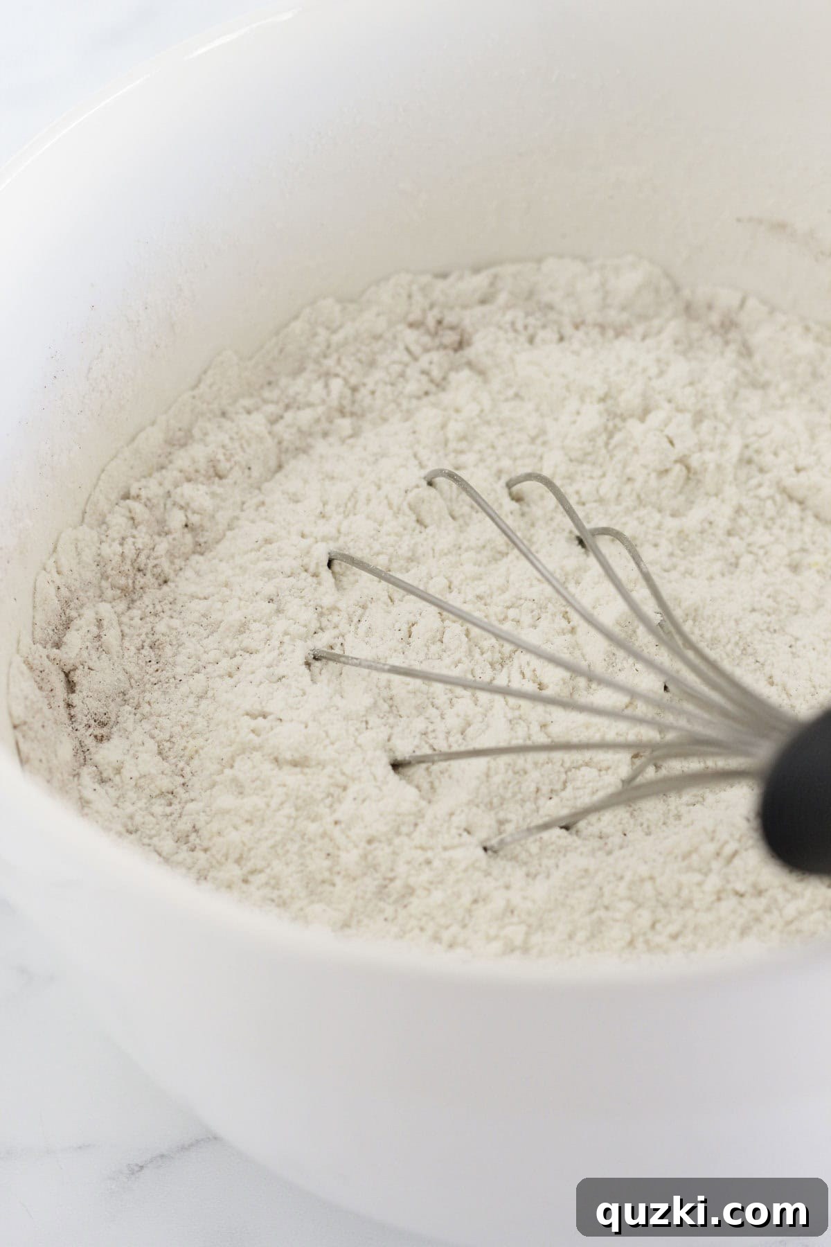 Whisking together dry ingredients: yellow cake mix and pumpkin pie spice in a large mixing bowl.