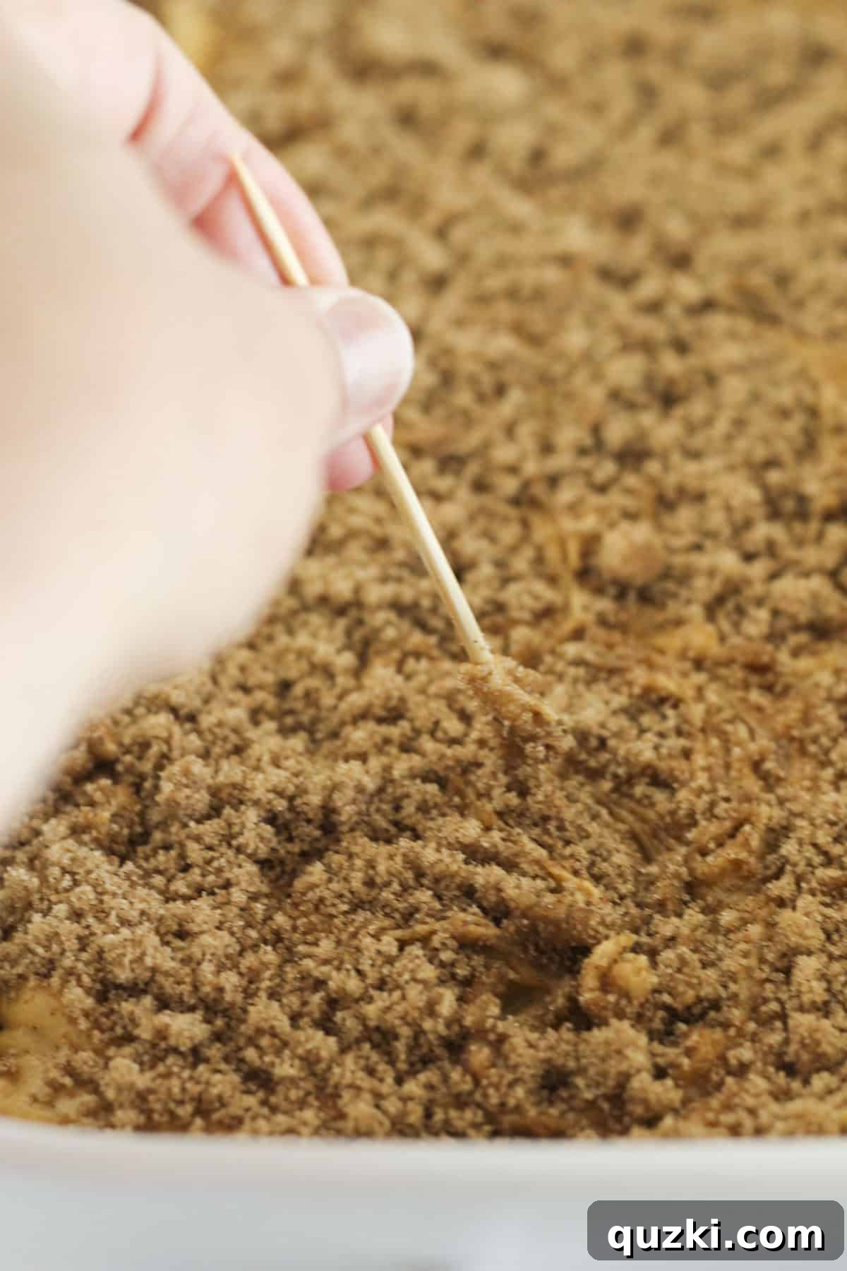Sprinkling the remaining cinnamon swirl mixture on top and swirling it into the cake batter with a wooden skewer to create a marble effect.