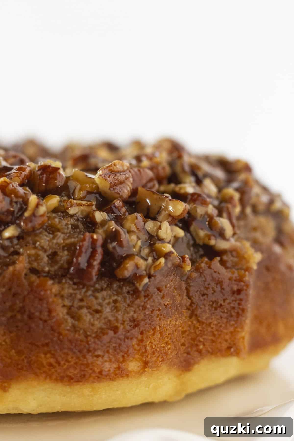 A beautifully inverted Pecan Upside Down Cake resting on a elegant cake plate, showcasing its golden caramel topping.