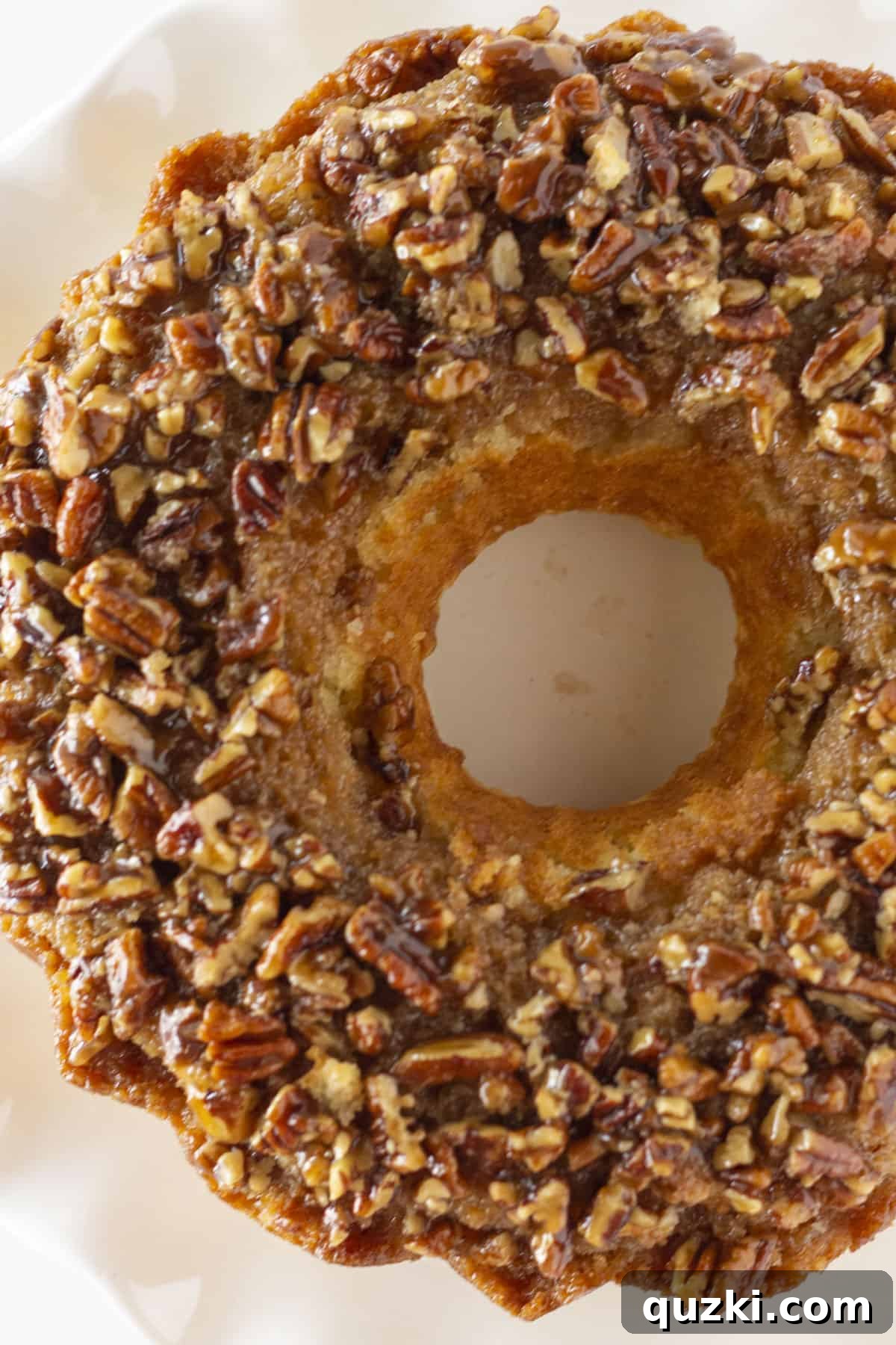 A close-up, overhead view of a Pecan Upside Down Cake, beautifully displayed on a pristine white cake plate.