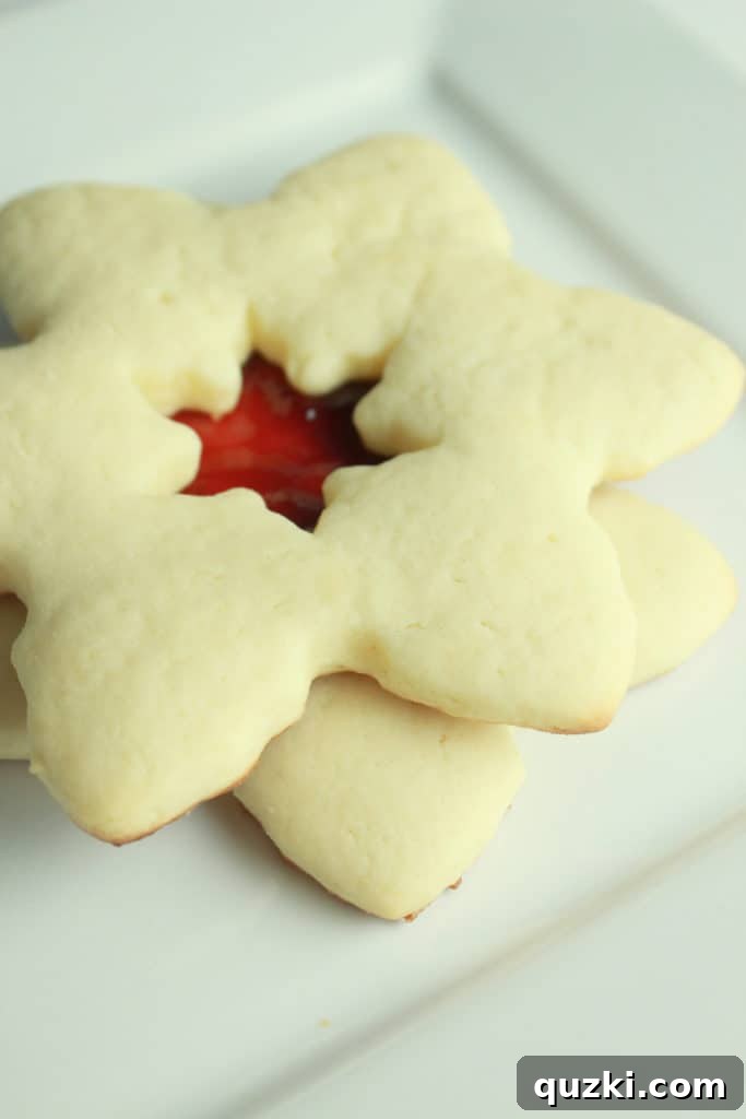 Cream Cheese Linzer Snowflakes 5 Cutting snowflake shapes from sugar cookie dough using cookie cutters for Linzer cookie tops and bottoms.
