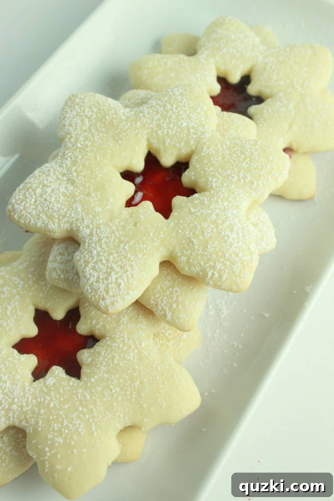 Cream Cheese Linzer Snowflakes 7 Applying a generous spoonful of raspberry jam onto the bottom half of a snowflake Linzer cookie.