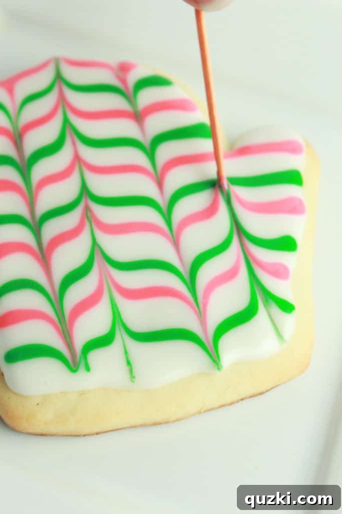 Sugar cookie with a intricate feathered pattern created by dragging a toothpick through lines of Glacé Icing.