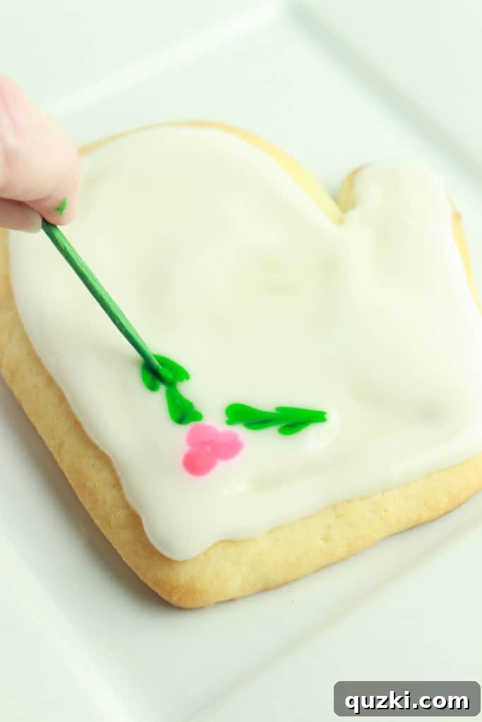 Sugar cookie decorated with festive holly leaves and berries made with Glacé Icing.