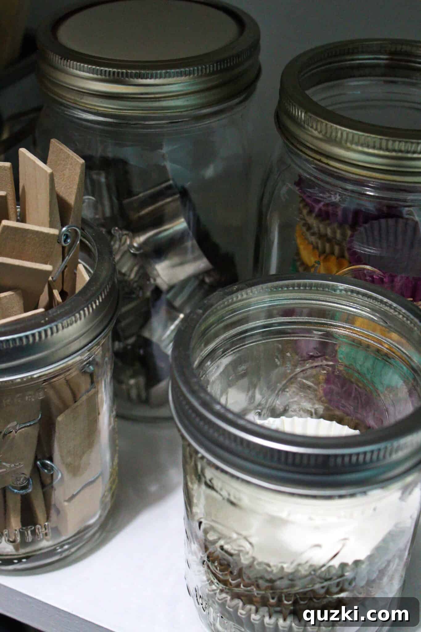 Pantry Organization Game-Changers 11 Assortment of cookie cutters and small kitchen gadgets neatly stored in Mason jars on a pantry shelf.
