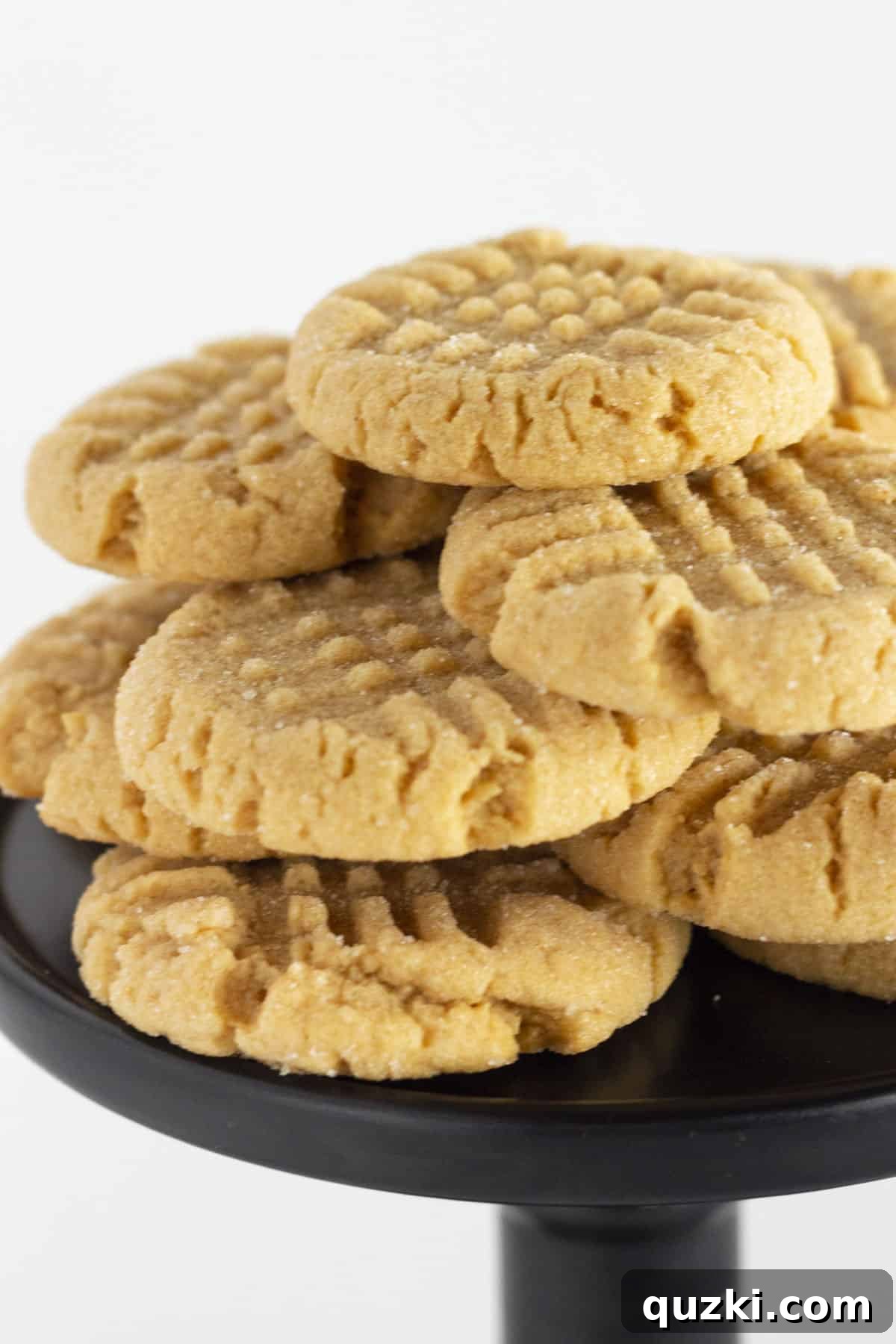 Peanut Butter Cake Mix Bliss 7 A black cake stand artfully displaying a stack of freshly baked, soft, and chewy peanut butter cake mix cookies.