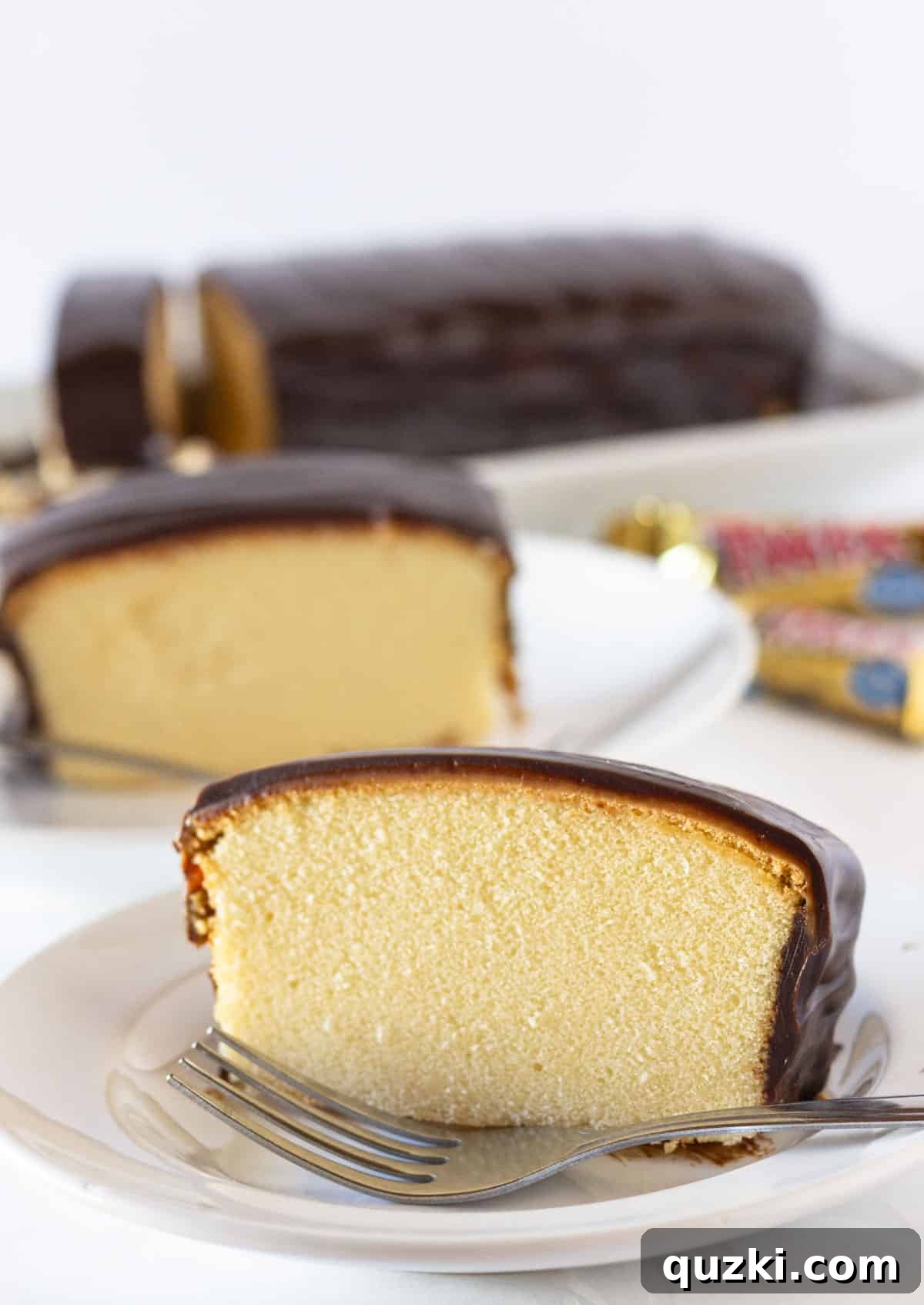 Two perfectly cut slices of No-Bake Twix Pound Cake on white plates, each with a fork.