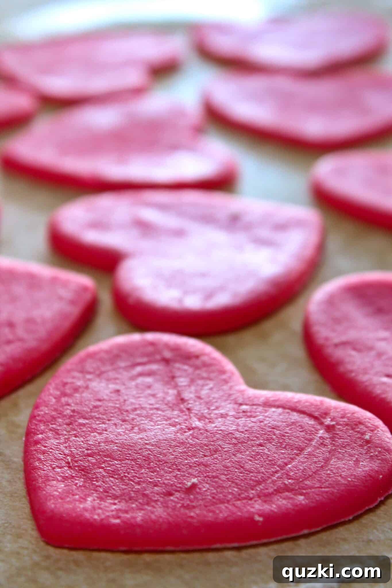 Removing excess pink dough around the cut heart shapes for Valentine's Day cookies