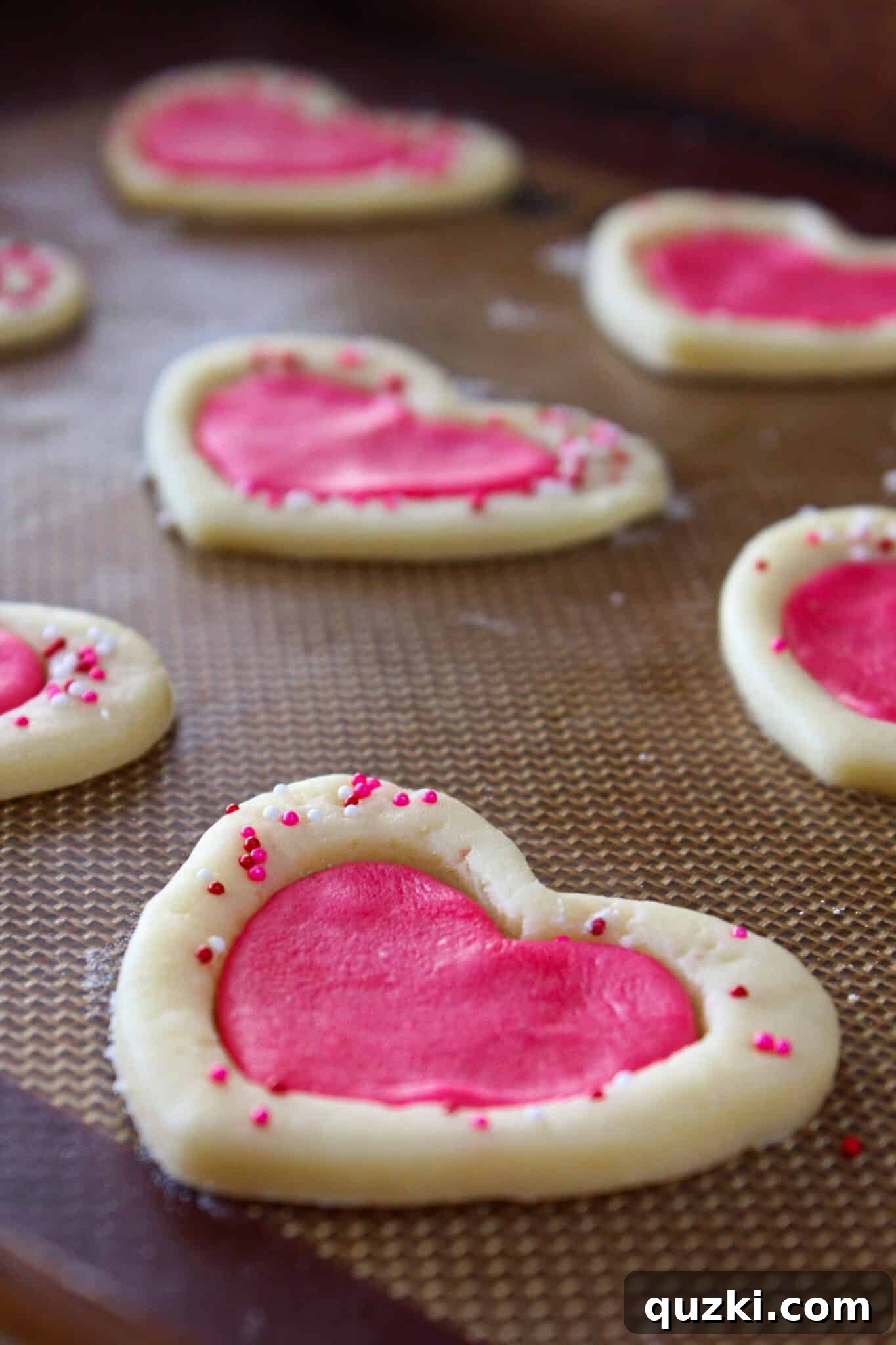 Assembling two-tone Valentine's Day sugar cookies: a white sprinkle outer heart with a pink inner heart