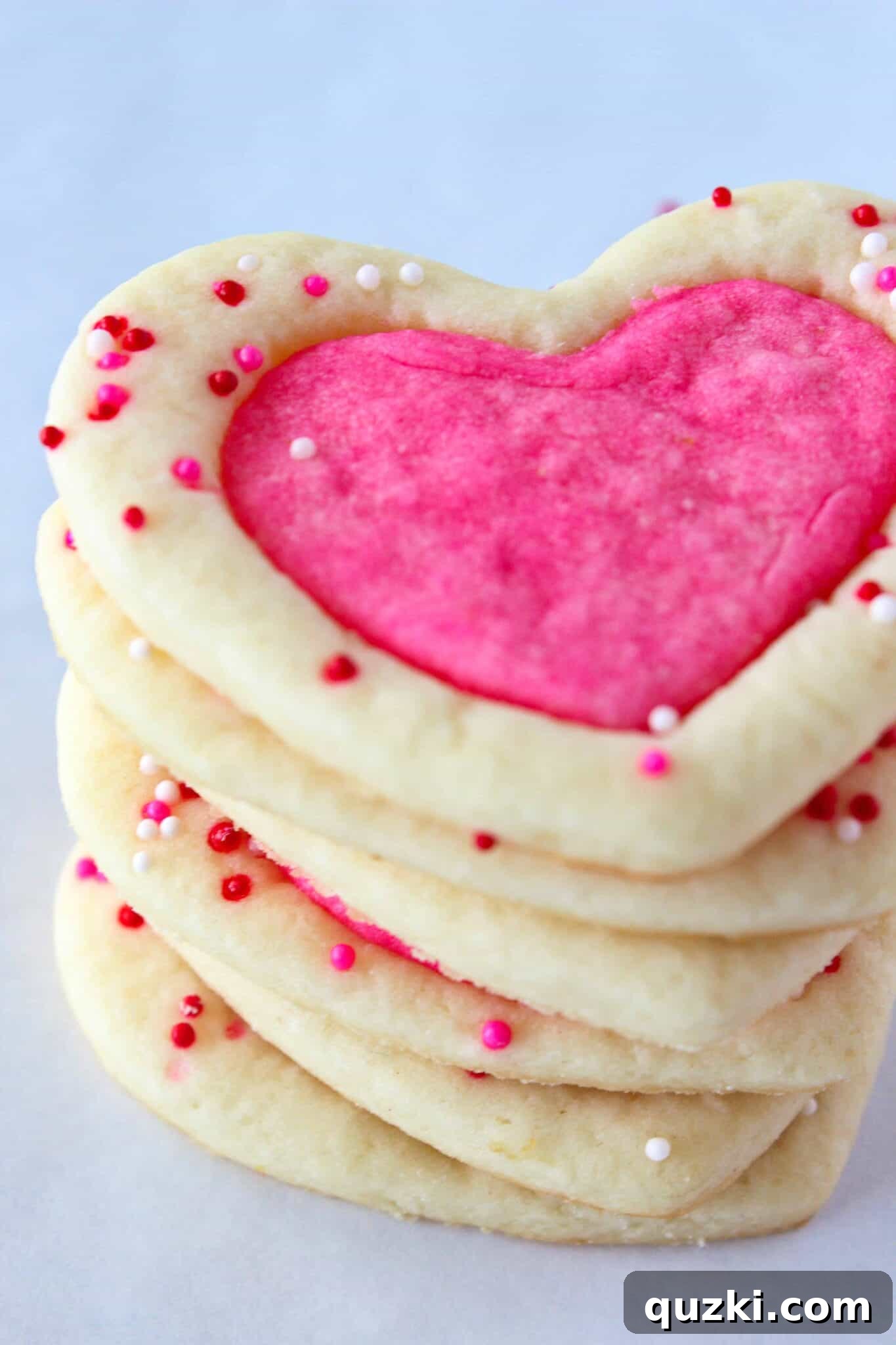 A plate of finished white sugar cookies with sprinkle outlines and solid pink centers