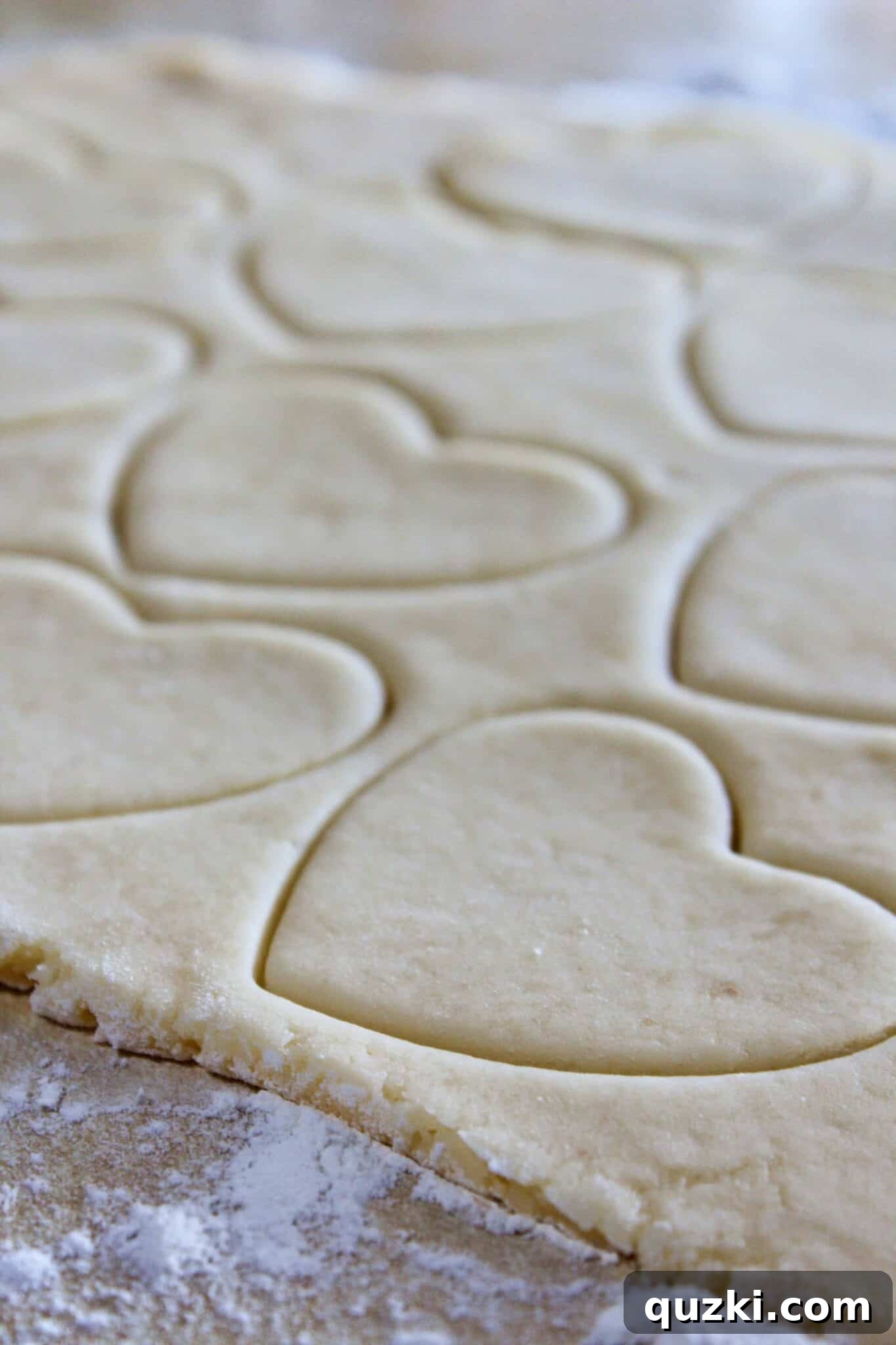 Rolling out white sugar cookie dough on a floured surface for Valentine's Day heart cookies