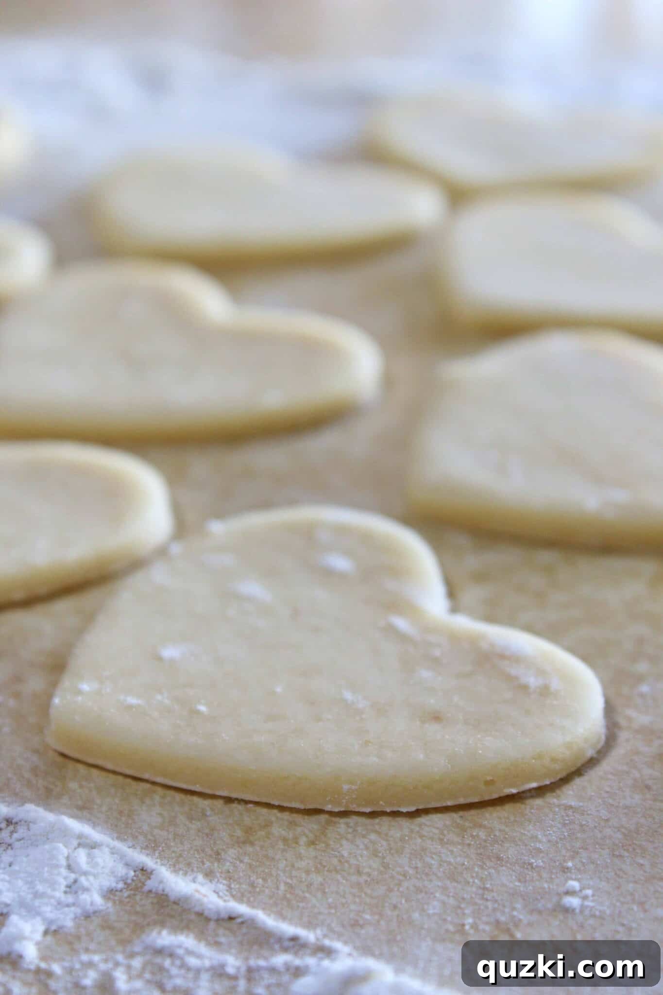 Removing excess dough around cut heart shapes, preparing for sprinkle application