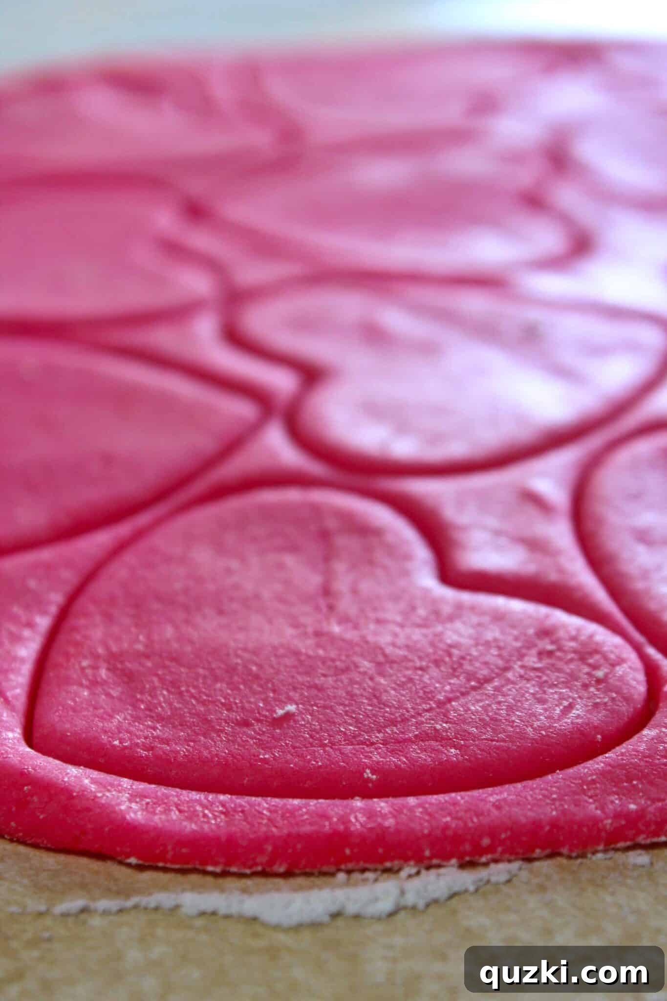 Rolling out pink sugar cookie dough on a floured surface for Valentine's Day treats