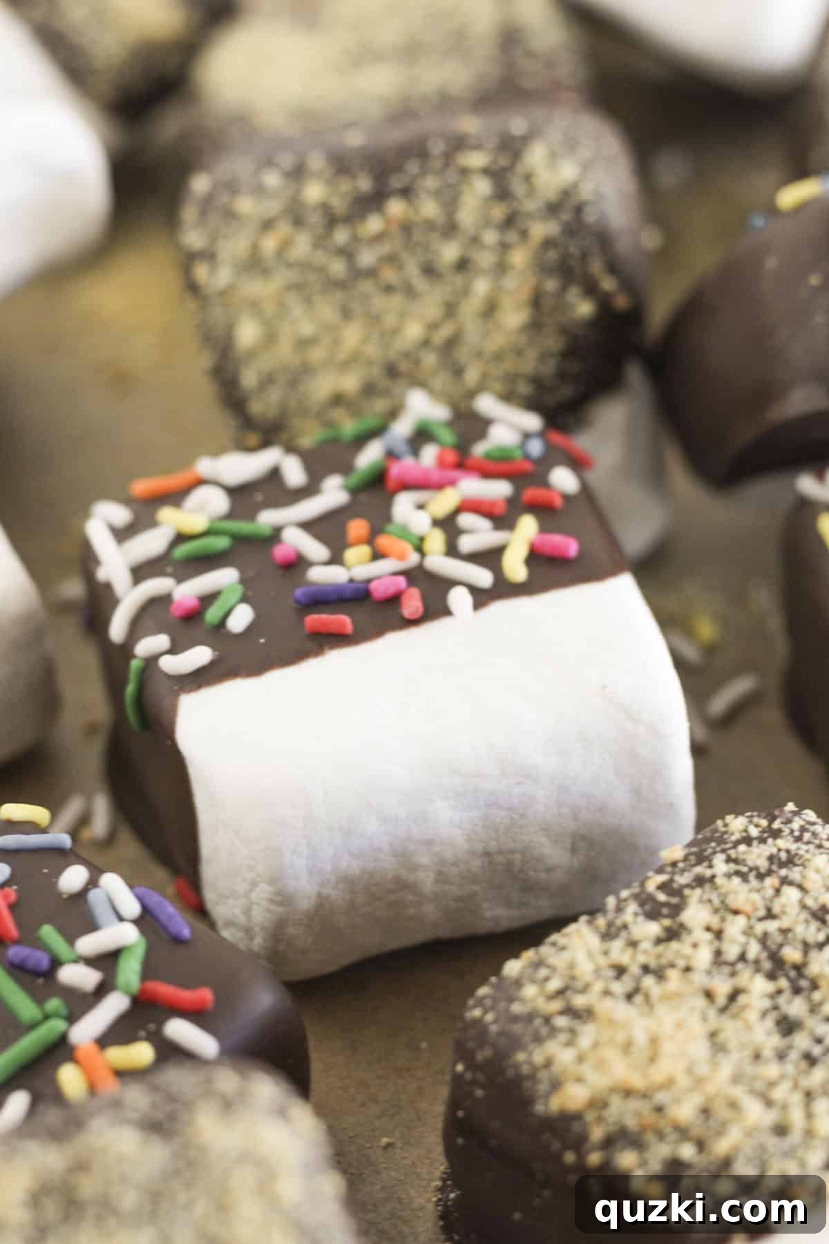 Easy Two-Ingredient Chocolate Dipped Marshmallows 2 Chocolate covered marshmallows with sprinkles drying on a cookie sheet, ready to be enjoyed.