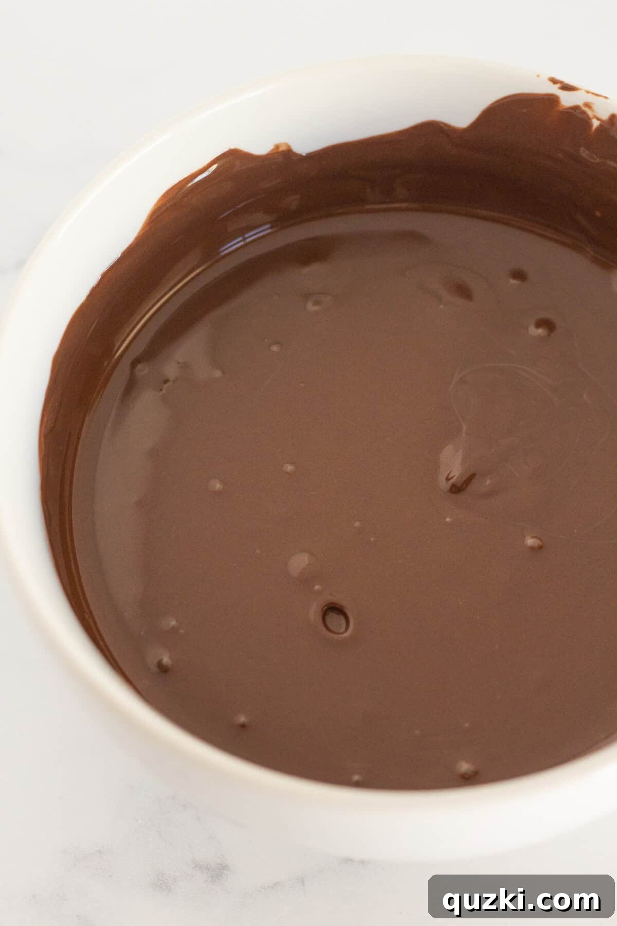 Easy Two-Ingredient Chocolate Dipped Marshmallows 4 Melted chocolate in a pristine white bowl, glistening and smooth, ready for dipping.