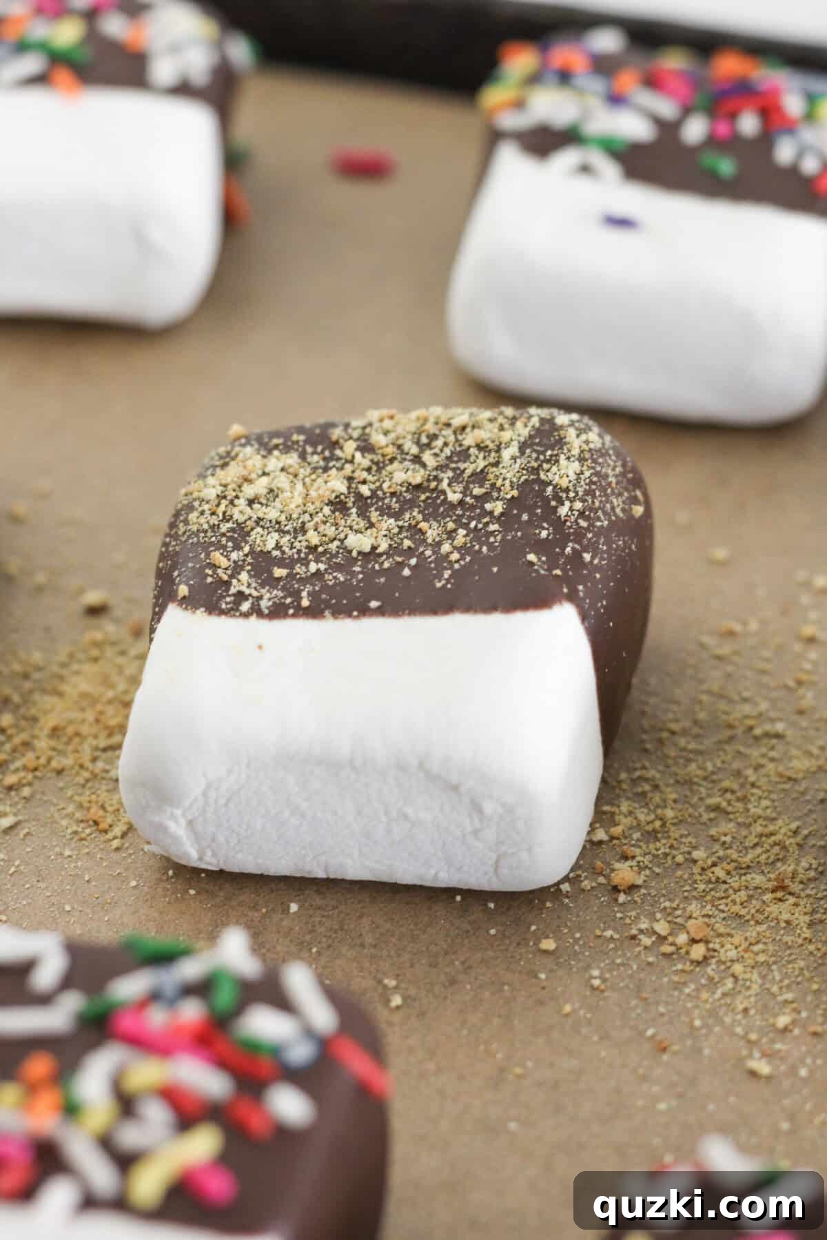 Easy Two-Ingredient Chocolate Dipped Marshmallows 7 A tray of chocolate dipped marshmallows, some with sprinkles, cooling and setting on parchment paper.