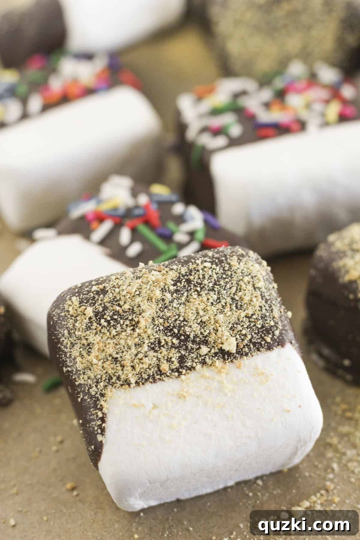 Easy Two-Ingredient Chocolate Dipped Marshmallows 8 A beautiful arrangement of chocolate dipped marshmallows with various delicious toppings on a white tray.