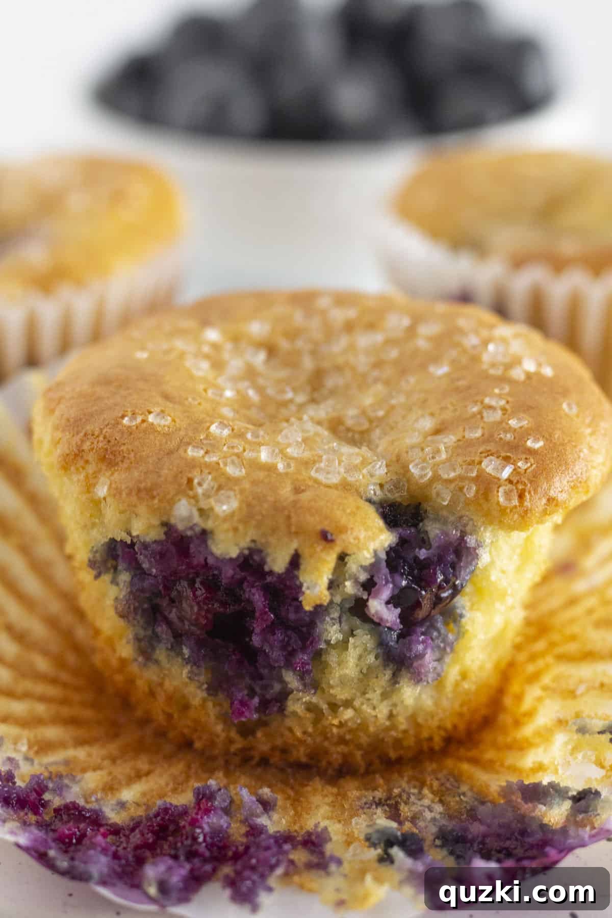 Effortless Blueberry Cake Mix Muffins 6 A baked muffin, with its cupcake liner gently removed, ready to be eaten.