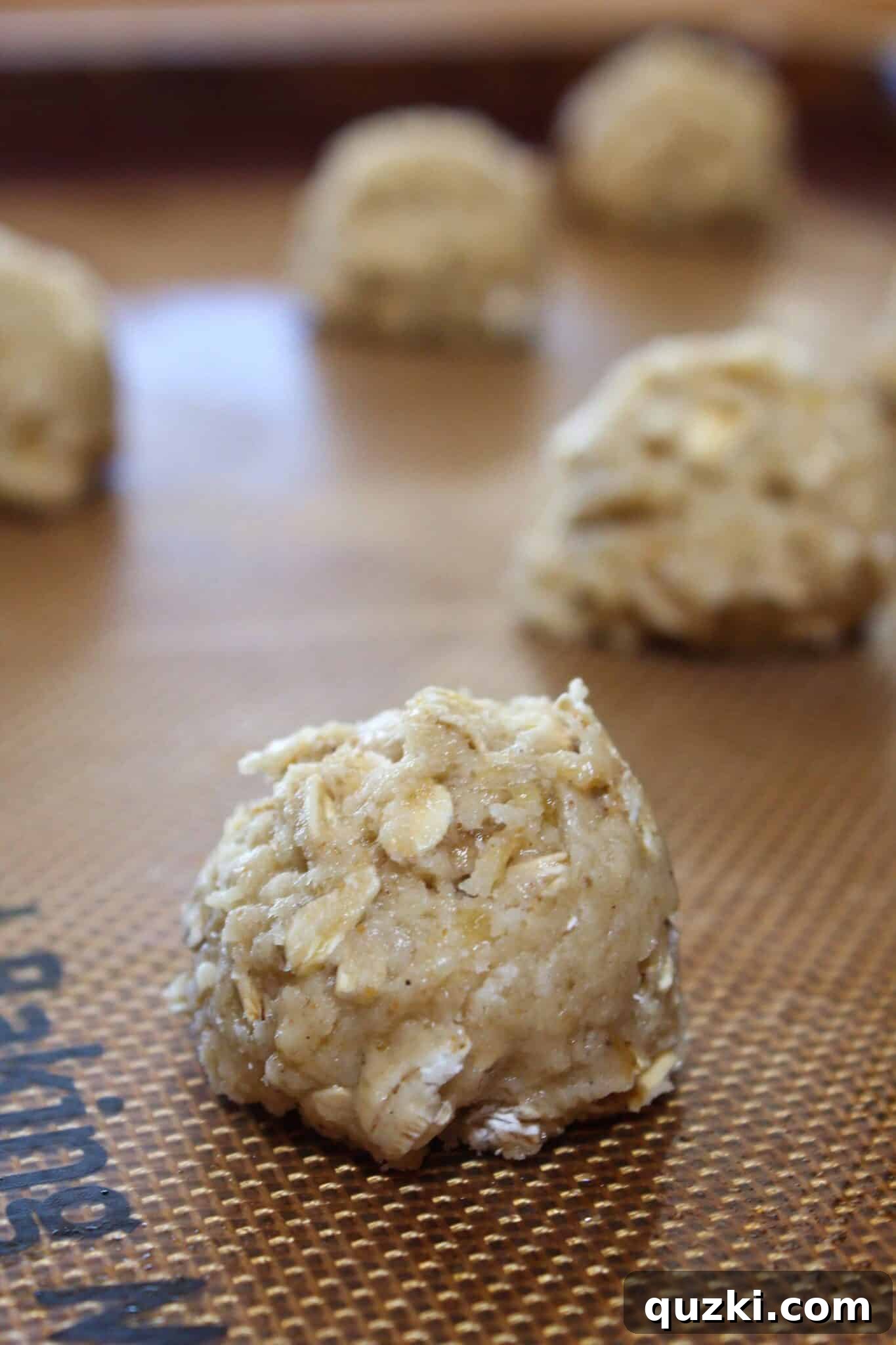 Nutty Brown Butter Banana Oatmeal Cookies 9 Mounds of brown butter banana oatmeal cookie dough scooped onto a baking sheet lined with a silicone mat, spaced for even baking.