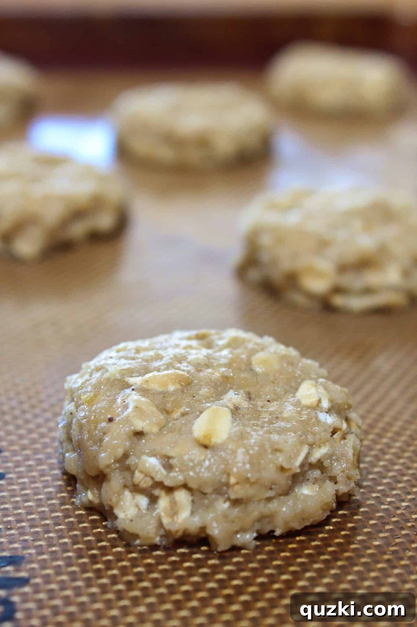 Nutty Brown Butter Banana Oatmeal Cookies 10 Cookie dough mounds on a baking sheet, slightly pressed down with fingers to ensure even baking and a perfect shape for brown butter banana oatmeal cookies.