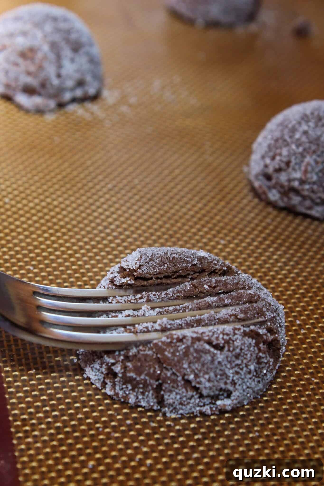 Prepared cookie dough mounds with fork indentations arranged neatly on a baking tray, perfectly ready for the oven.