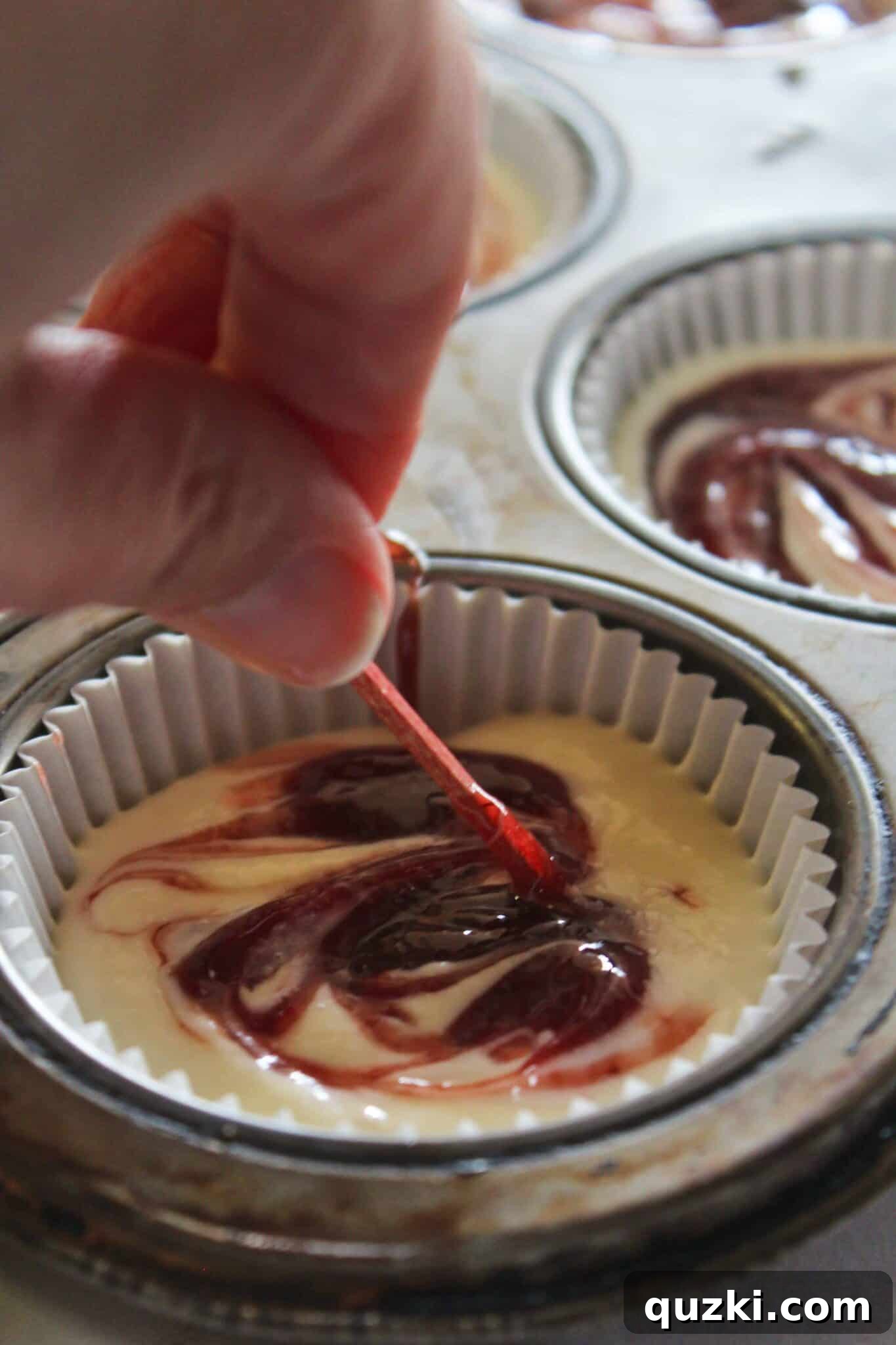 Decadent Mini Raspberry Cheesecake Cups 11 Toothpick swirling raspberry jam into the mini cheesecake batter for a marbled effect.