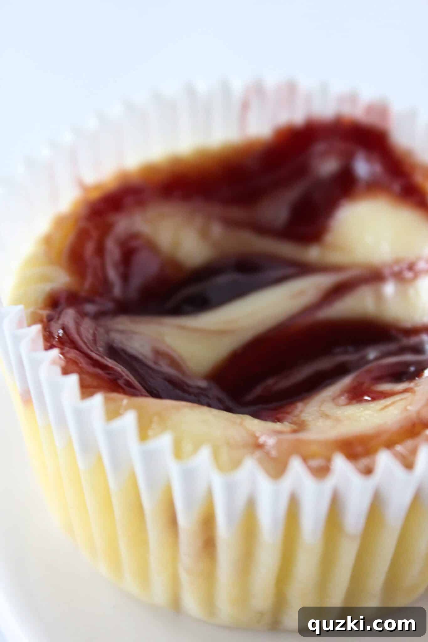 Decadent Mini Raspberry Cheesecake Cups 15 Close-up of a Mini Raspberry Cheesecake revealing the layers of Golden Oreo crust and raspberry swirled filling.
