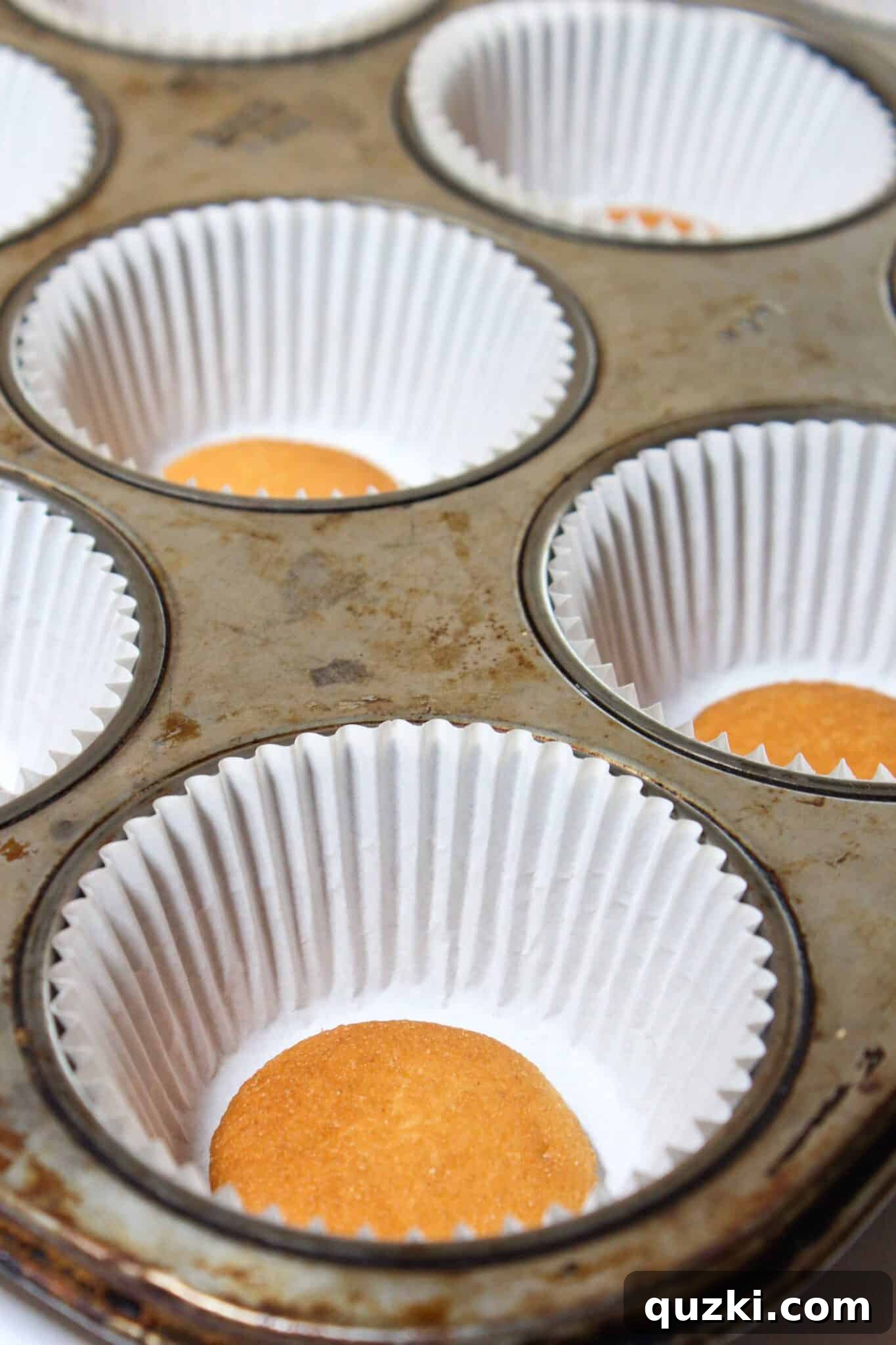Decadent Mini Raspberry Cheesecake Cups 7 Dividing cheesecake batter into muffin liners with a cookie scoop.