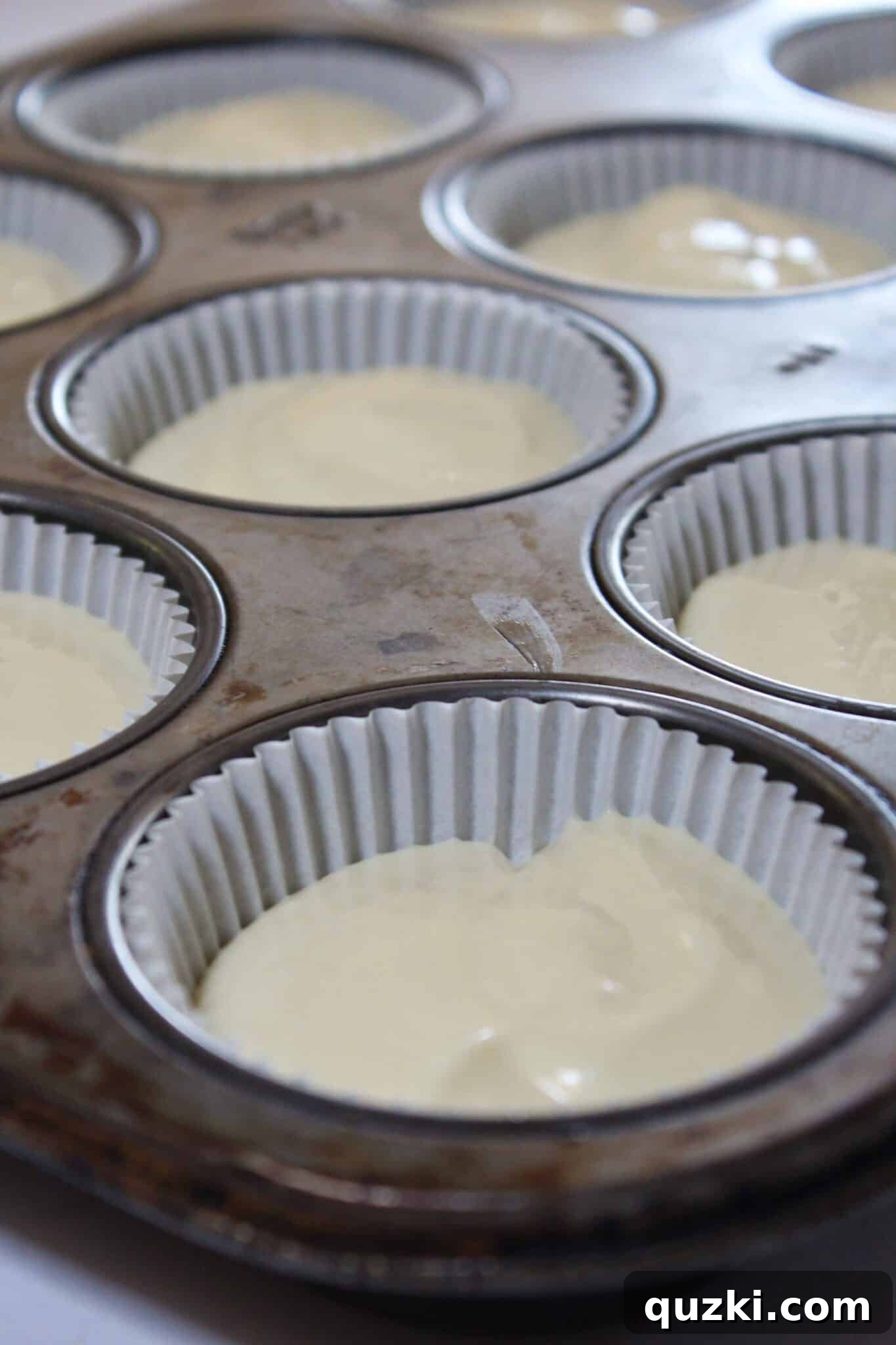 Decadent Mini Raspberry Cheesecake Cups 8 Cheesecake batter divided evenly in muffin liners, ready for the raspberry swirl.