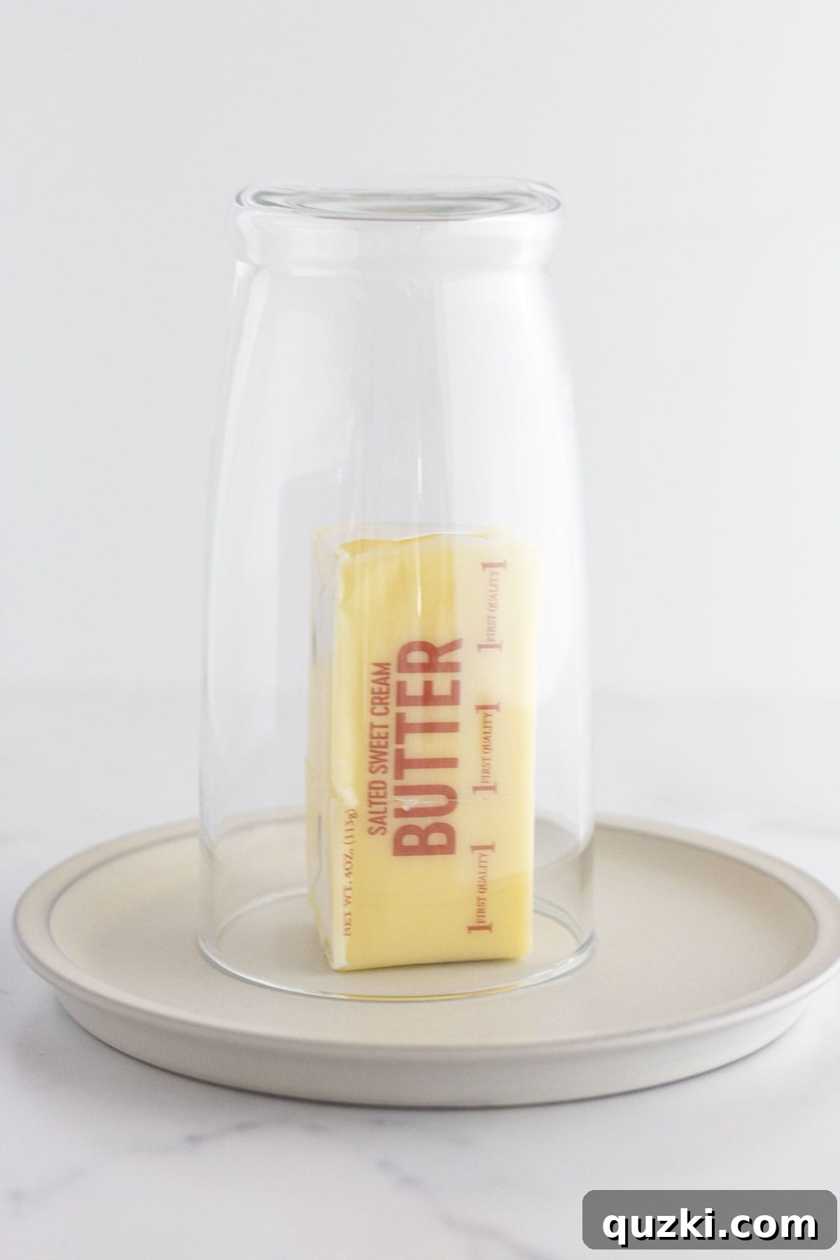 A warm glass cup placed over a stick of cold butter to bring it to room temperature quickly for baking.
