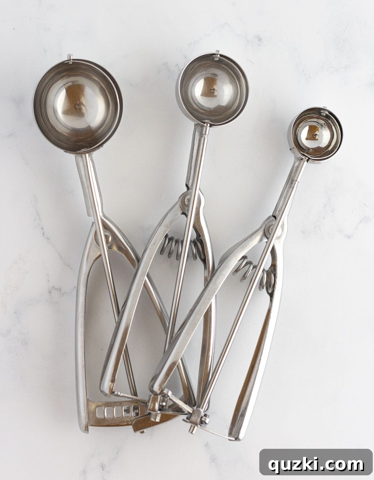 Three different sizes of cookie scoops lined up, showing options for various cookie sizes.