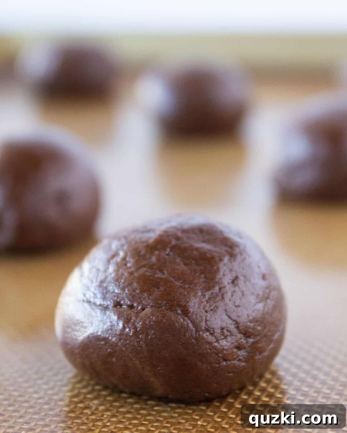 Evenly spaced cookie dough balls on a baking sheet, ready for the oven.