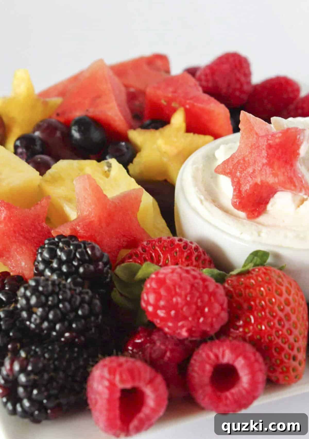 A festive fruit tray with fresh fruit, some cut into star shapes and cheesecake dip, perfect for 4th of July.
