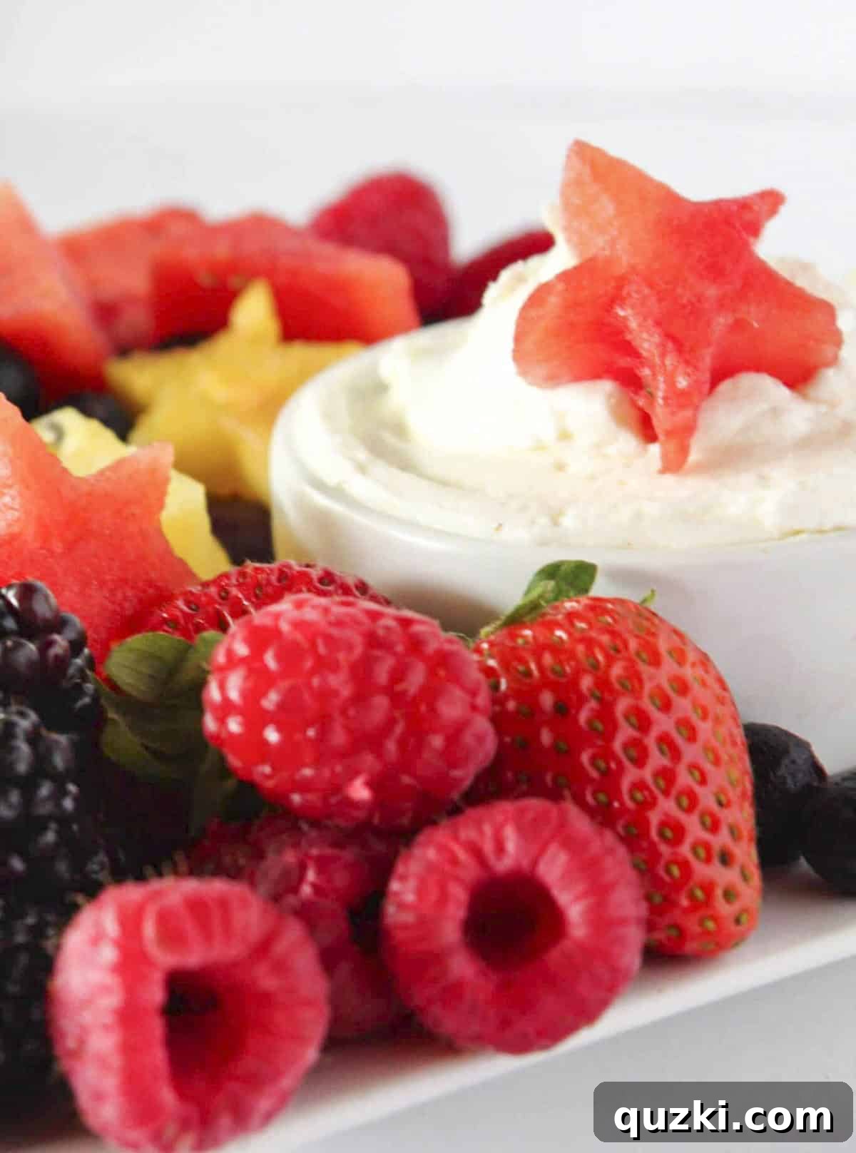 A close up of a patriotic fruit tray with a small bowl of creamy dip.