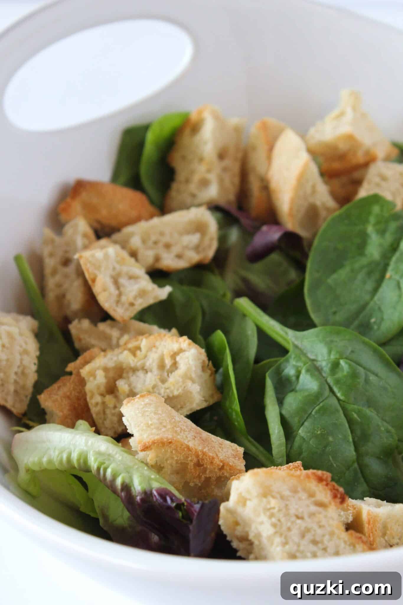 Quick Bruschetta Salad 11 Arranging homemade garlic croutons around the perimeter of the fresh mixed greens in a large serving bowl, preparing for the bruschetta topping.