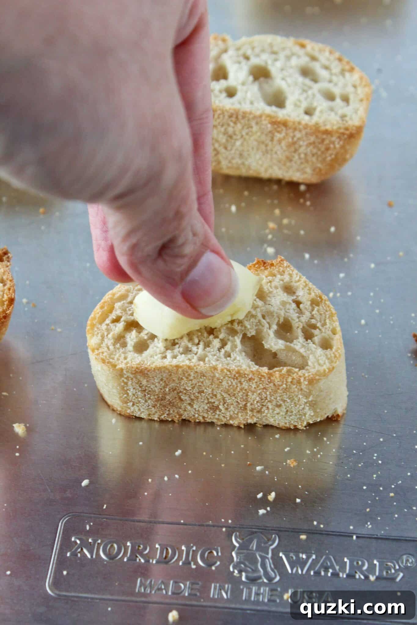 Quick Bruschetta Salad 9 A hand rubbing a peeled garlic clove over warm, golden-brown toasted baguette slices to infuse them with rich garlic flavor.