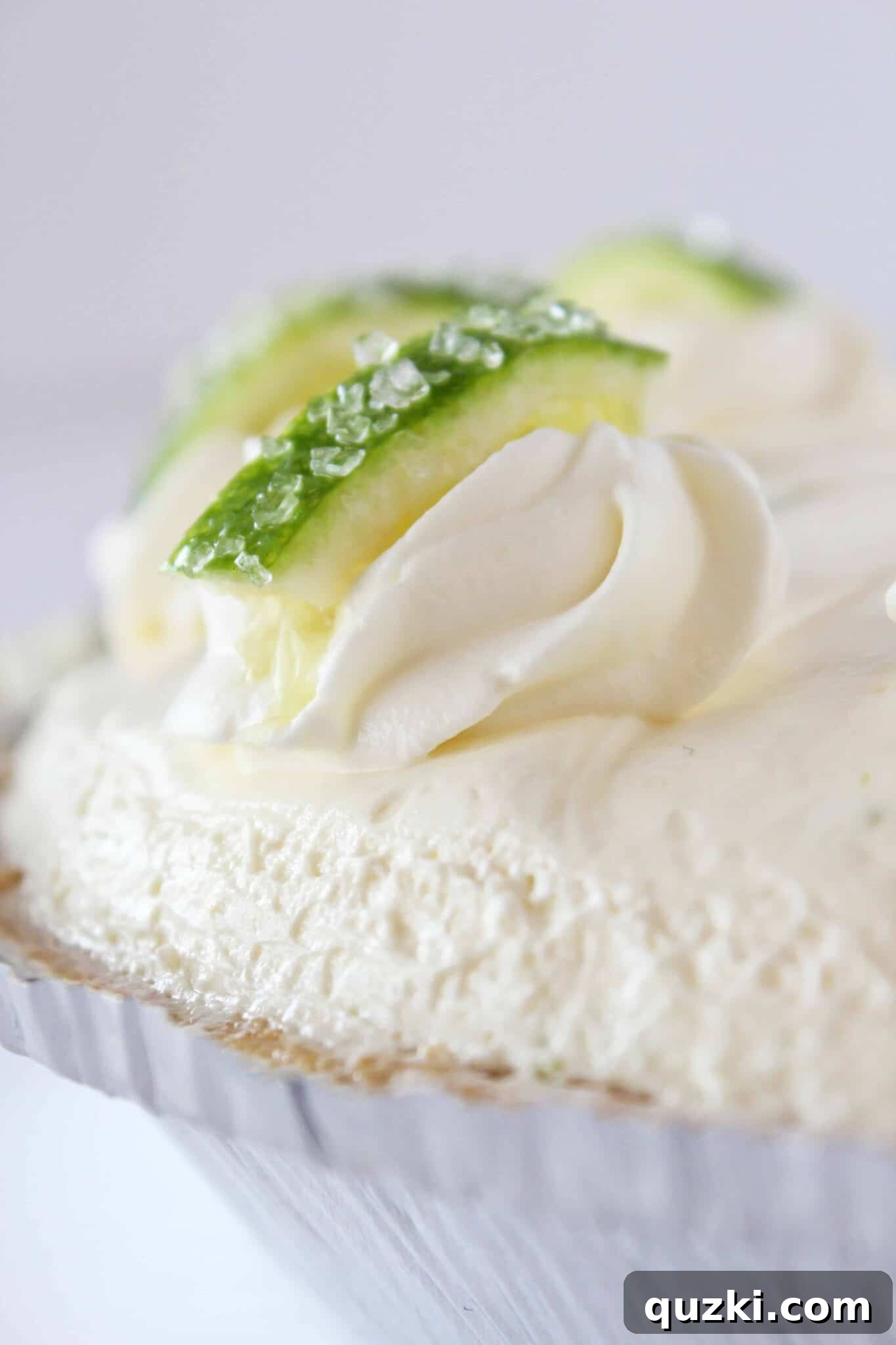 Effortless Margarita Cheesecake Dream 2 A finished no bake margarita cheesecake with swirls of whipped cream, garnished with lime slices.
