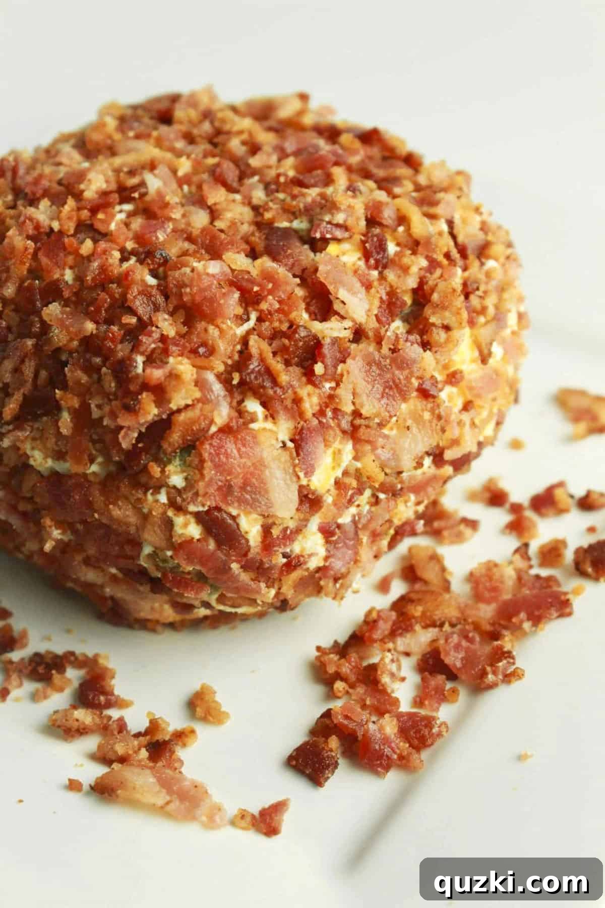 Game Day Jalapeño Popper Dip 6 A close-up shot of a magnificent Jalapeño Popper Cheese Ball, adorned with a generous, enticing layer of crispy bacon, perfectly presented on a serving plate.