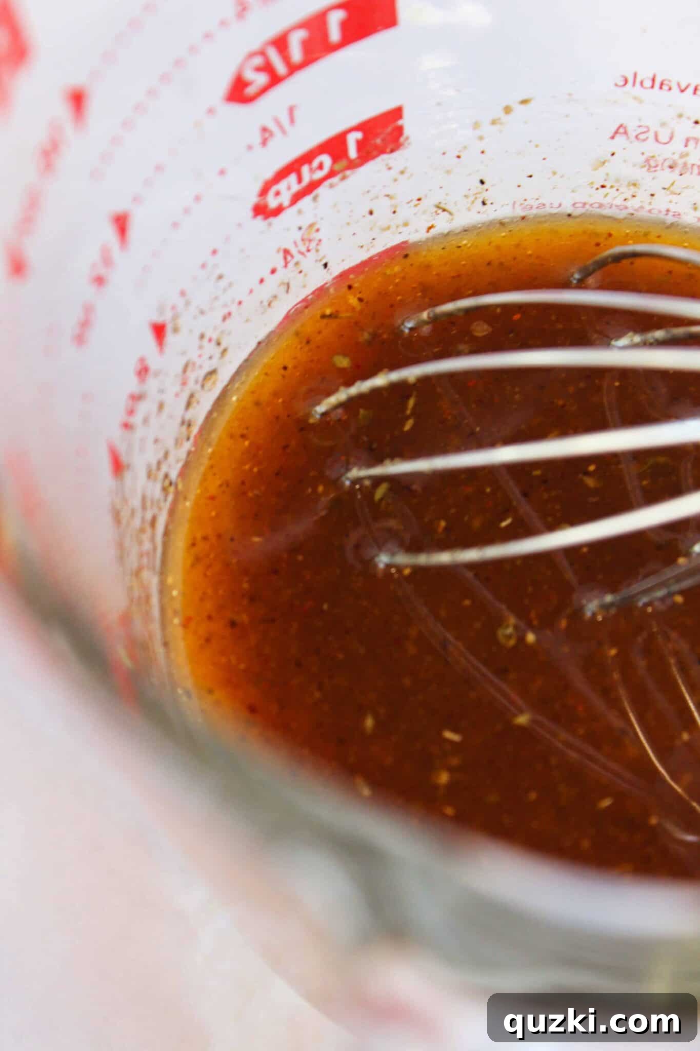 Simple Marinade for Succulent Chicken 5 A whisk blending together the flavorful ingredients for the chicken marinade in a clear glass measuring cup.