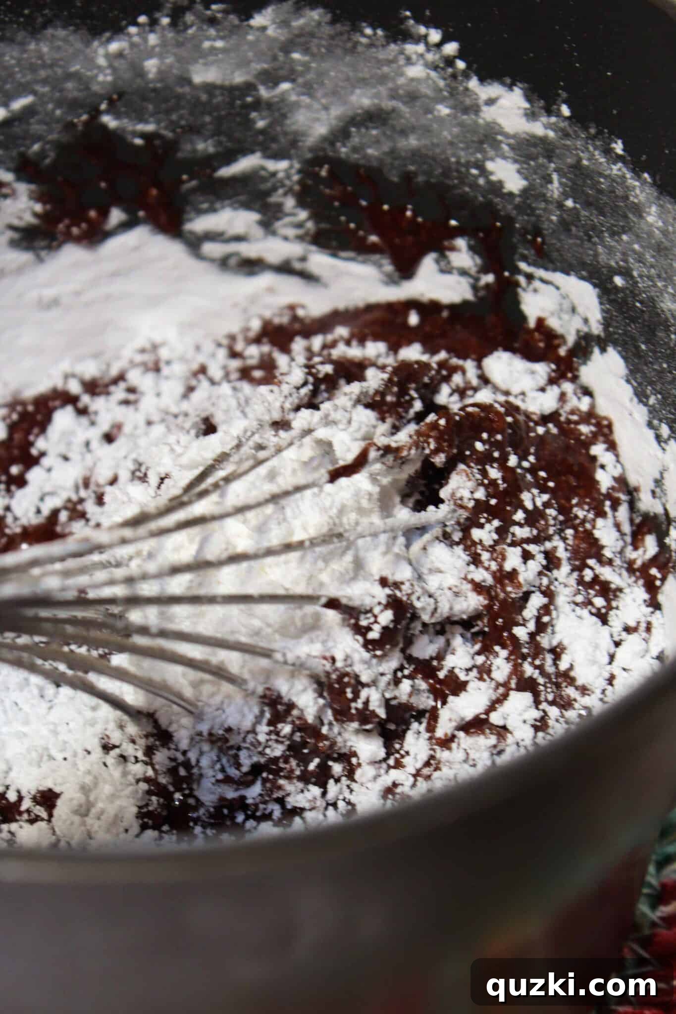 Mixing powdered sugar and vanilla into cooked chocolate frosting