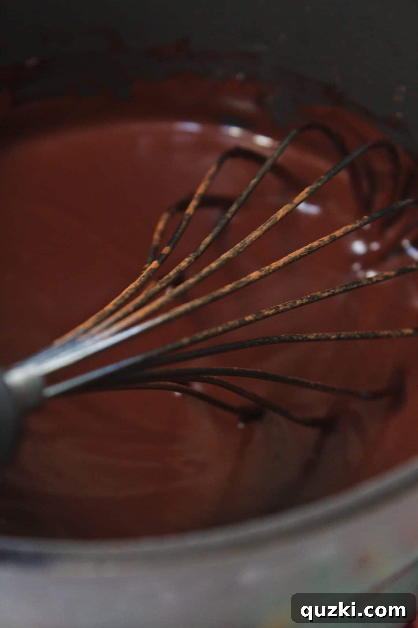 Whisking milk and cocoa into melted butter for cooked frosting