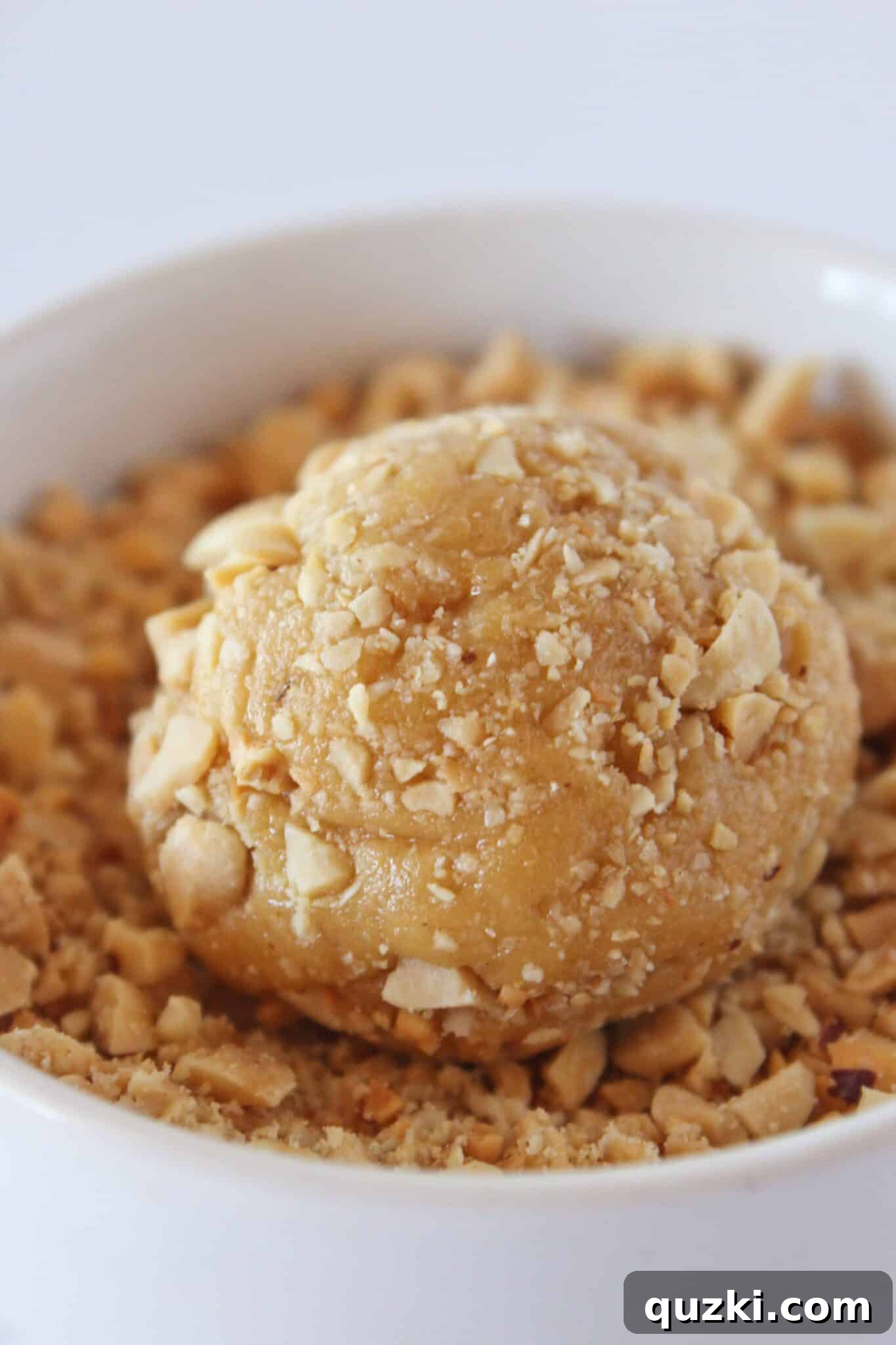 Hand rolling peanut butter cookie dough in chopped peanuts.