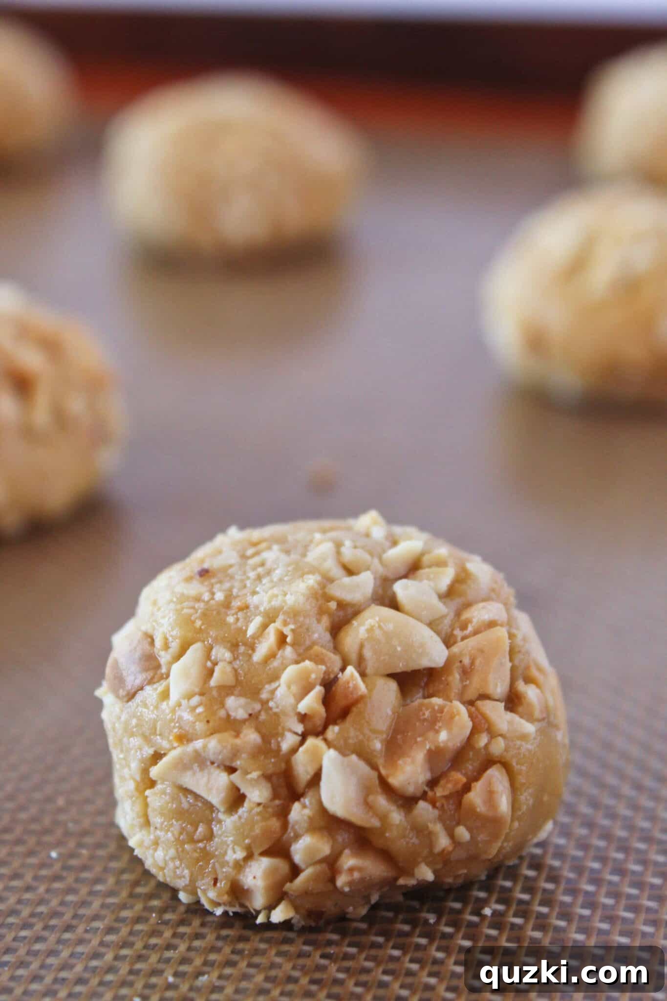 Placing the peanut-coated cookie dough balls on a baking sheet.