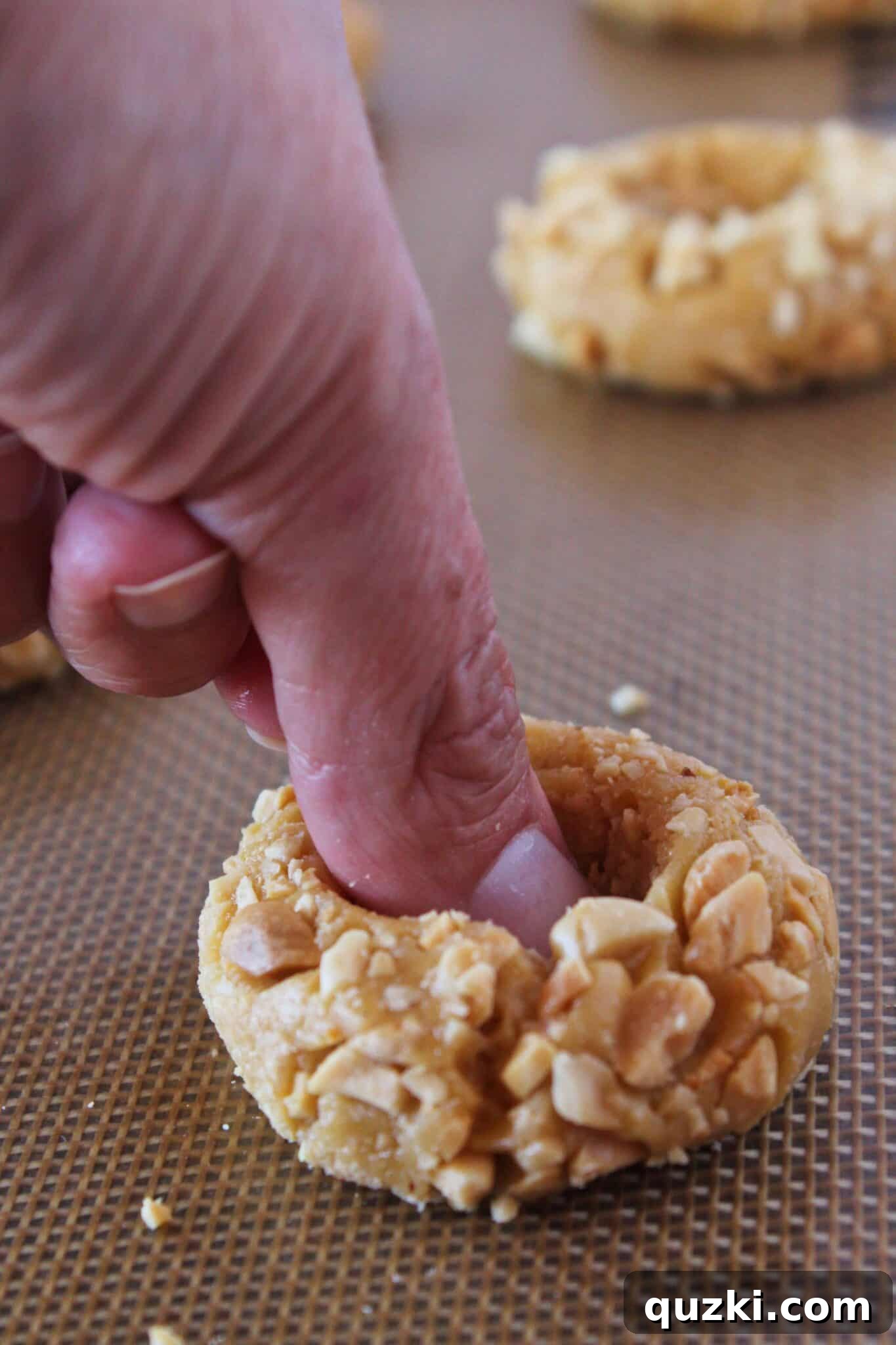 Making an indentation with a thumb in the center of a cookie dough ball.