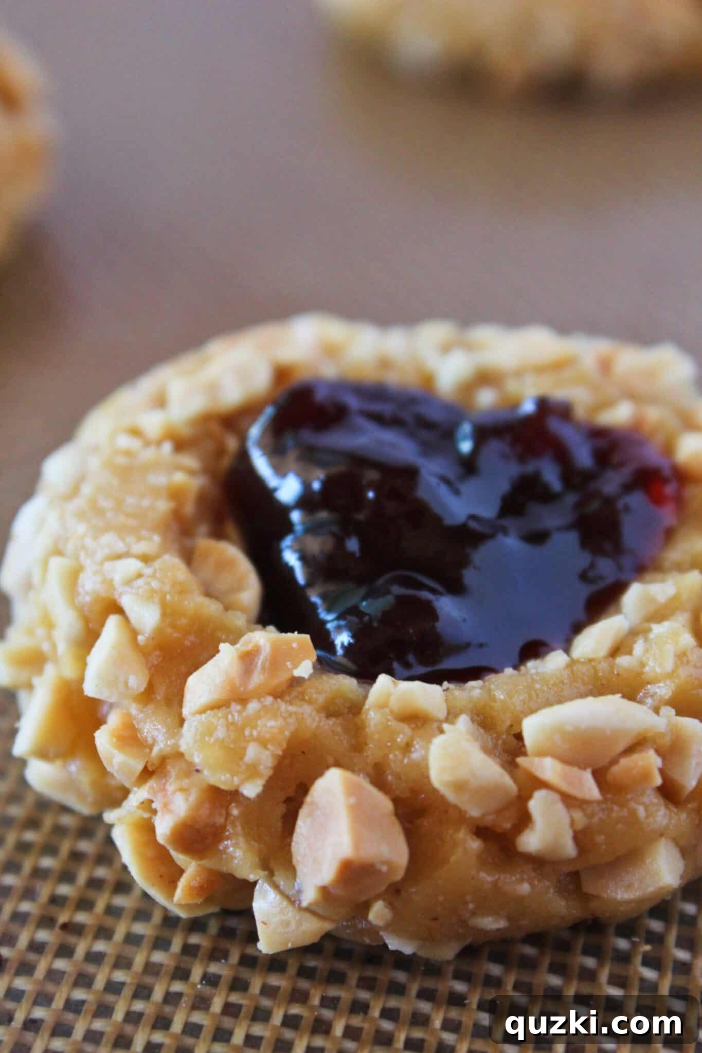 Adding raspberry jam to the indentations of each cookie dough ball.