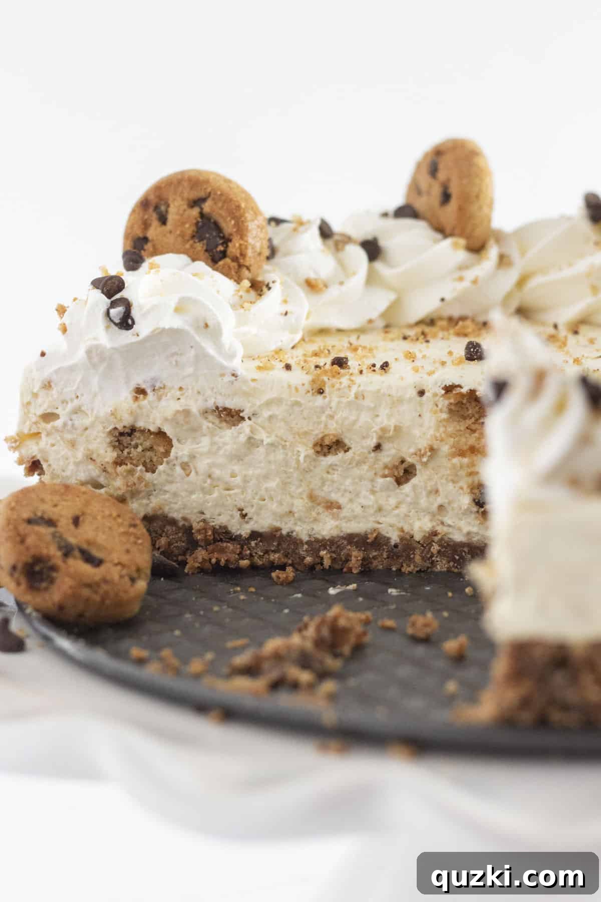 Looking inside a chocolate chip cookie cheesecake once a few pieces are removed, showcasing its creamy filling and cookie chunks.