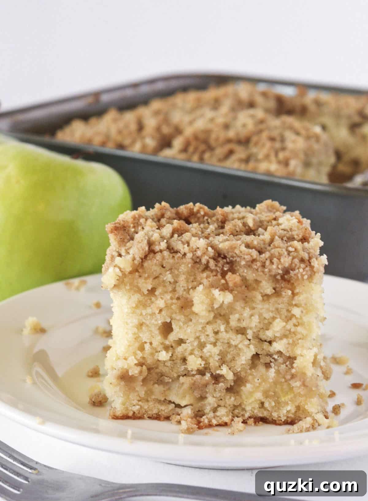 Homestyle Apple Streusel Cake 7 Serving a generous slice of apple crumb cake directly from the pan, highlighting its comforting appeal.
