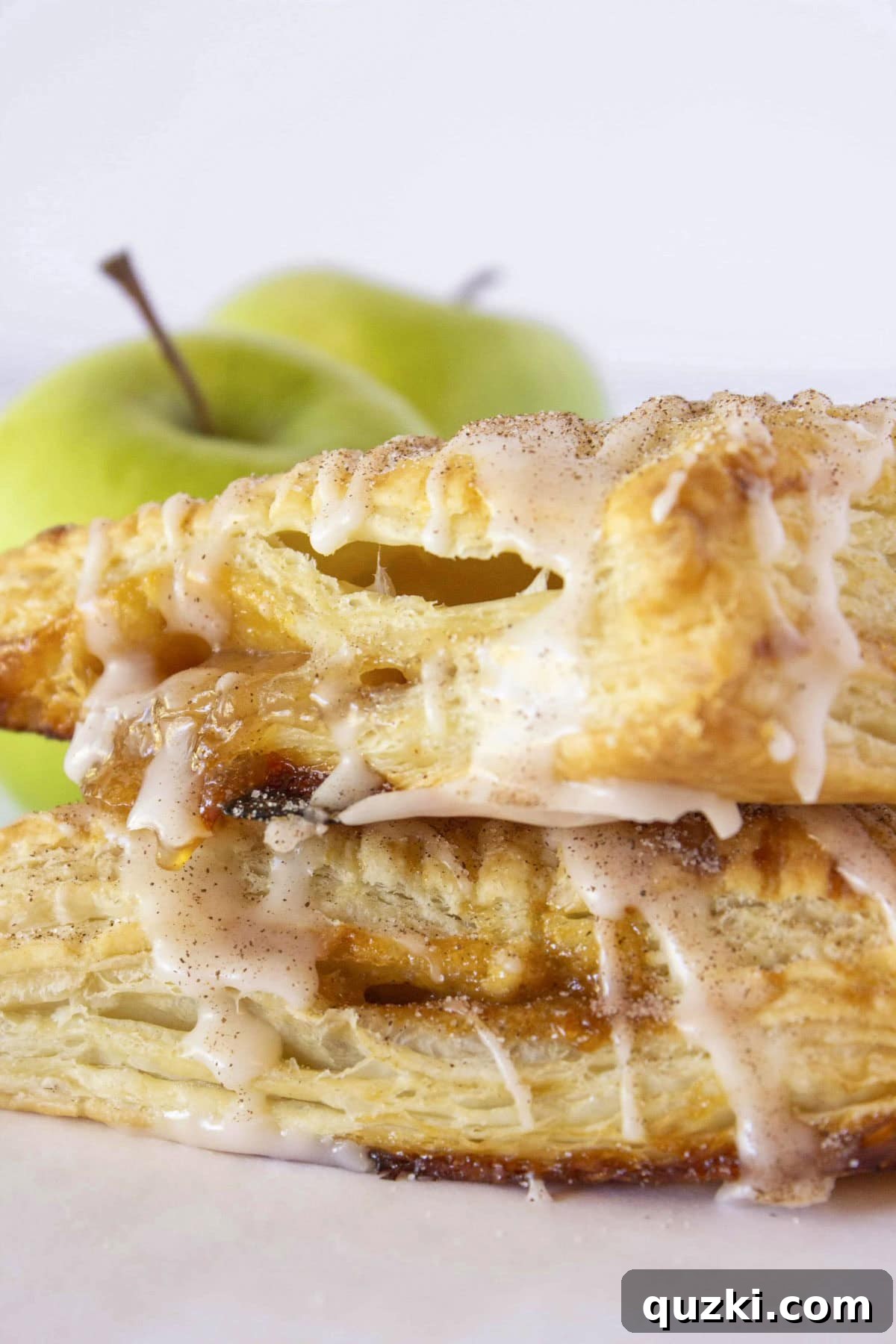 Sweet & Simple Caramel Apple Turnovers 2 Two golden-brown, flaky caramel apple turnovers stacked on each other, showing a hint of the delicious apple and caramel filling.